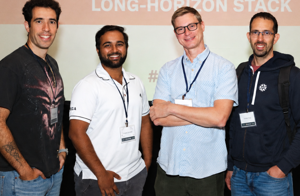 Four Opsin team members standing side by side at an event; they wear event badges and casual clothes.