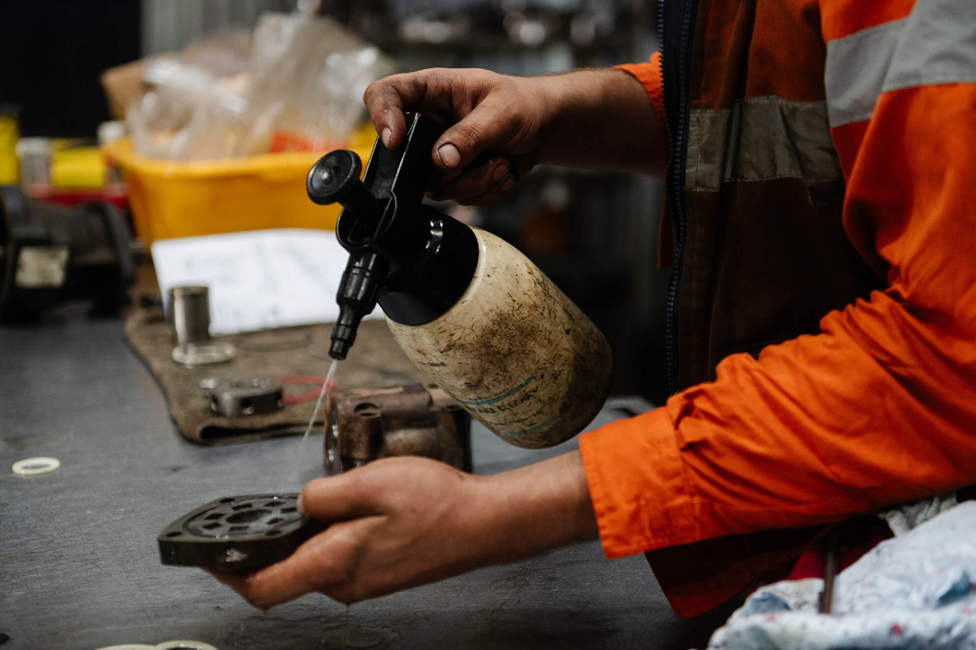 Worker applying lubricant to hydraulic part during repair process.