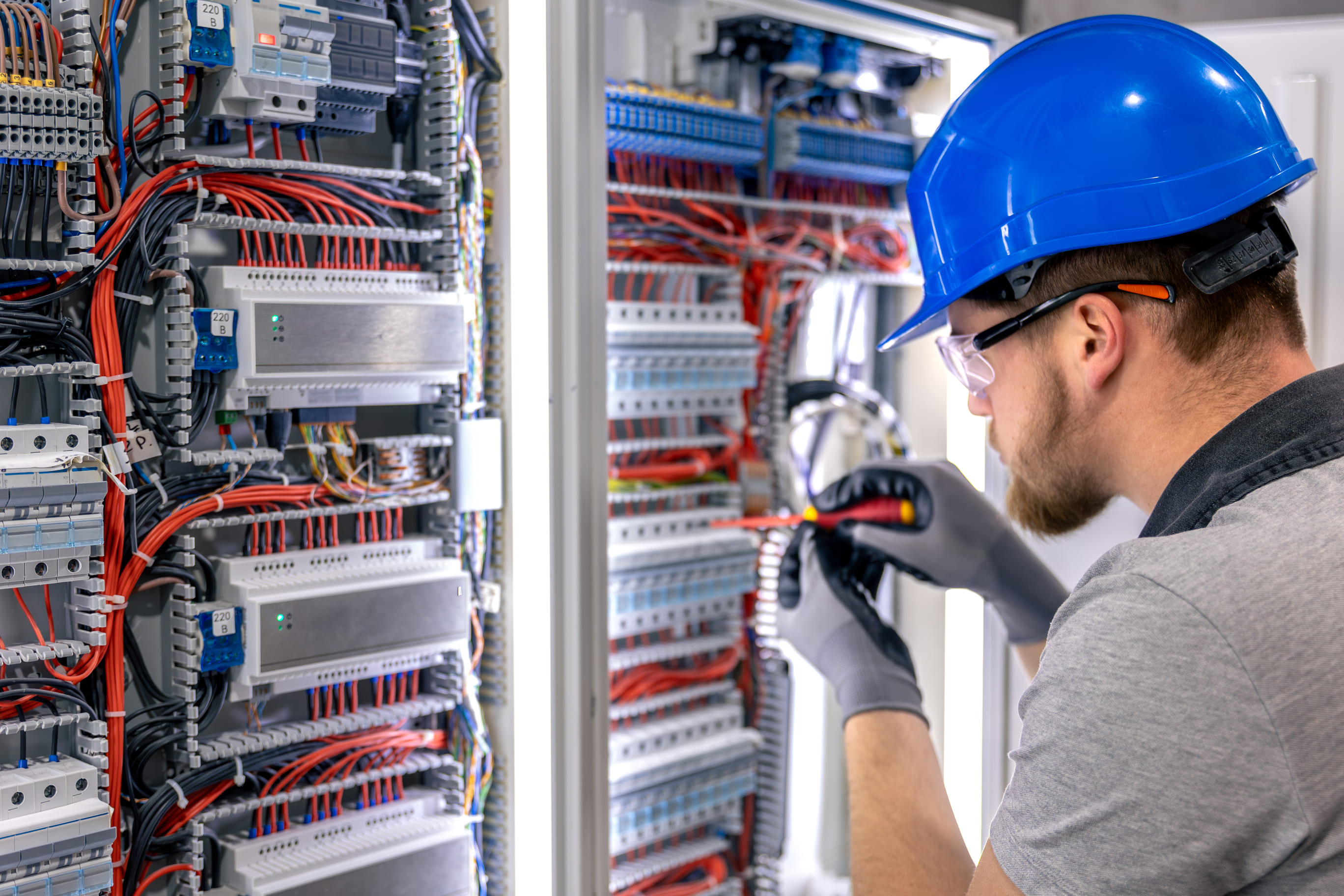 Male electrician in uniform working in a switchboard electricity