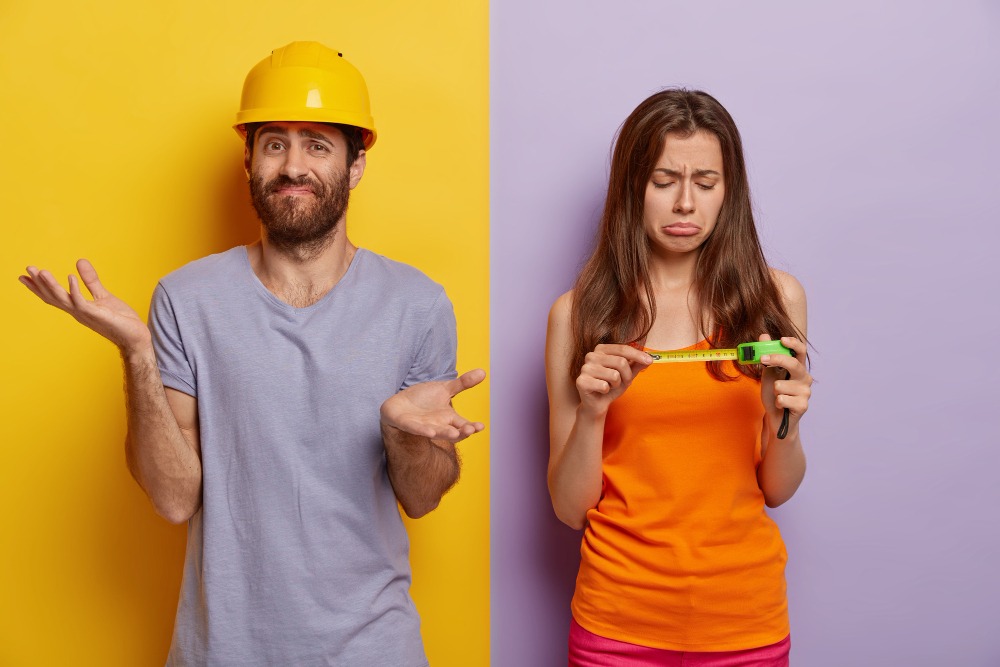 A man in a hard hat next to a woman holding a measuring tape