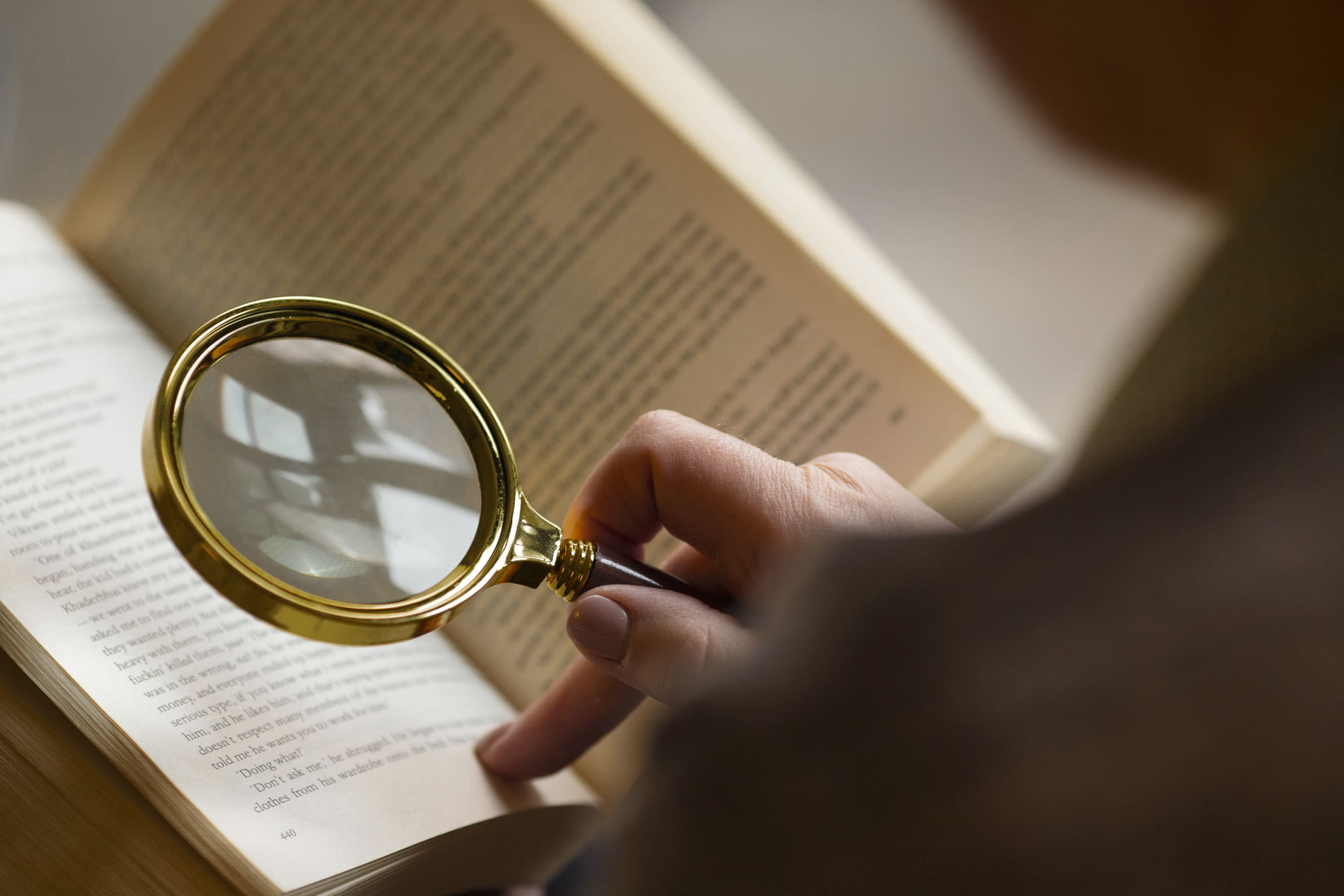 Reading old book using magnifying glass