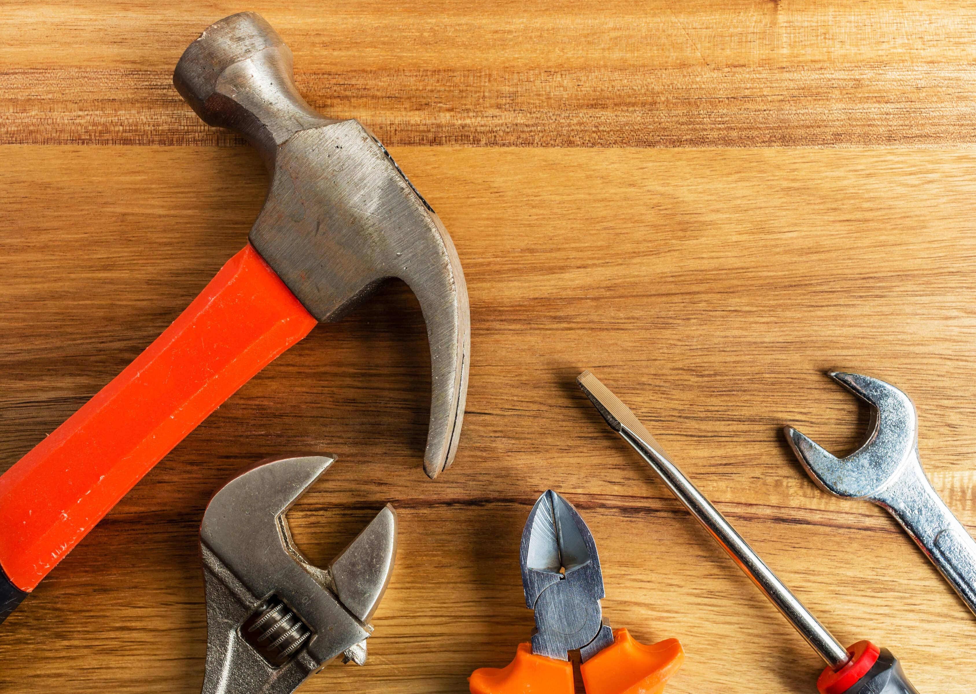 High angle shot of a hammer a screwdriver and other tools on a wooden surf