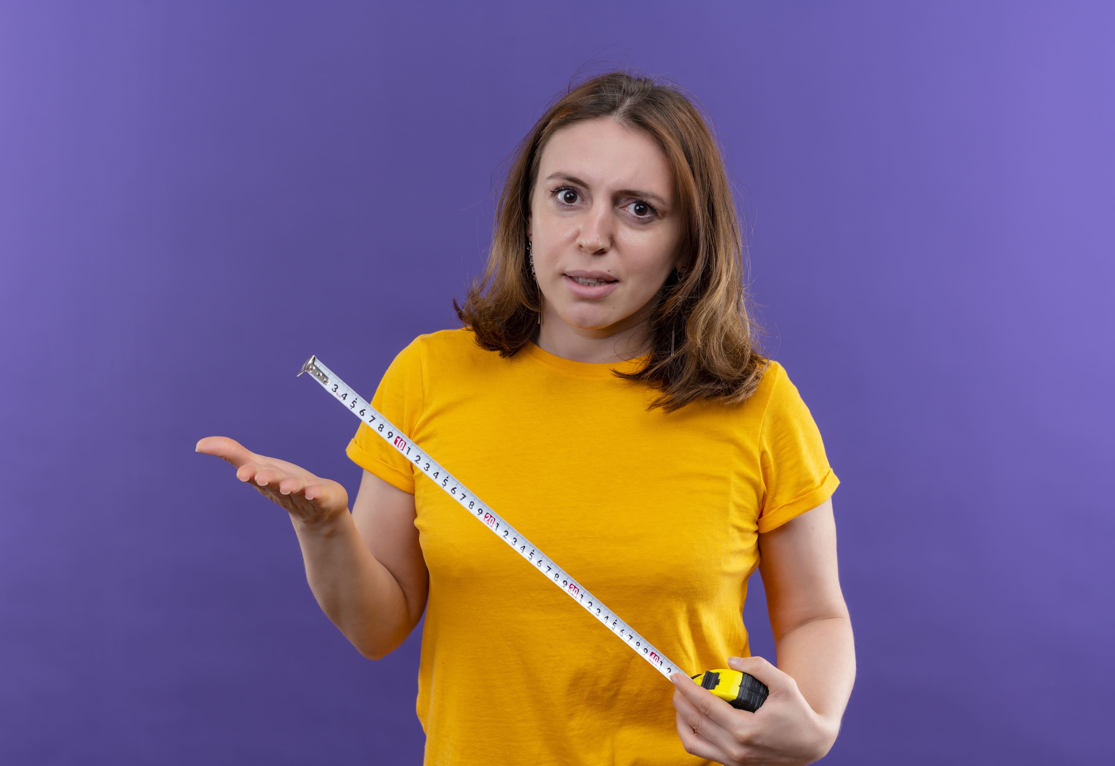 Woman holding tape measure looking confused