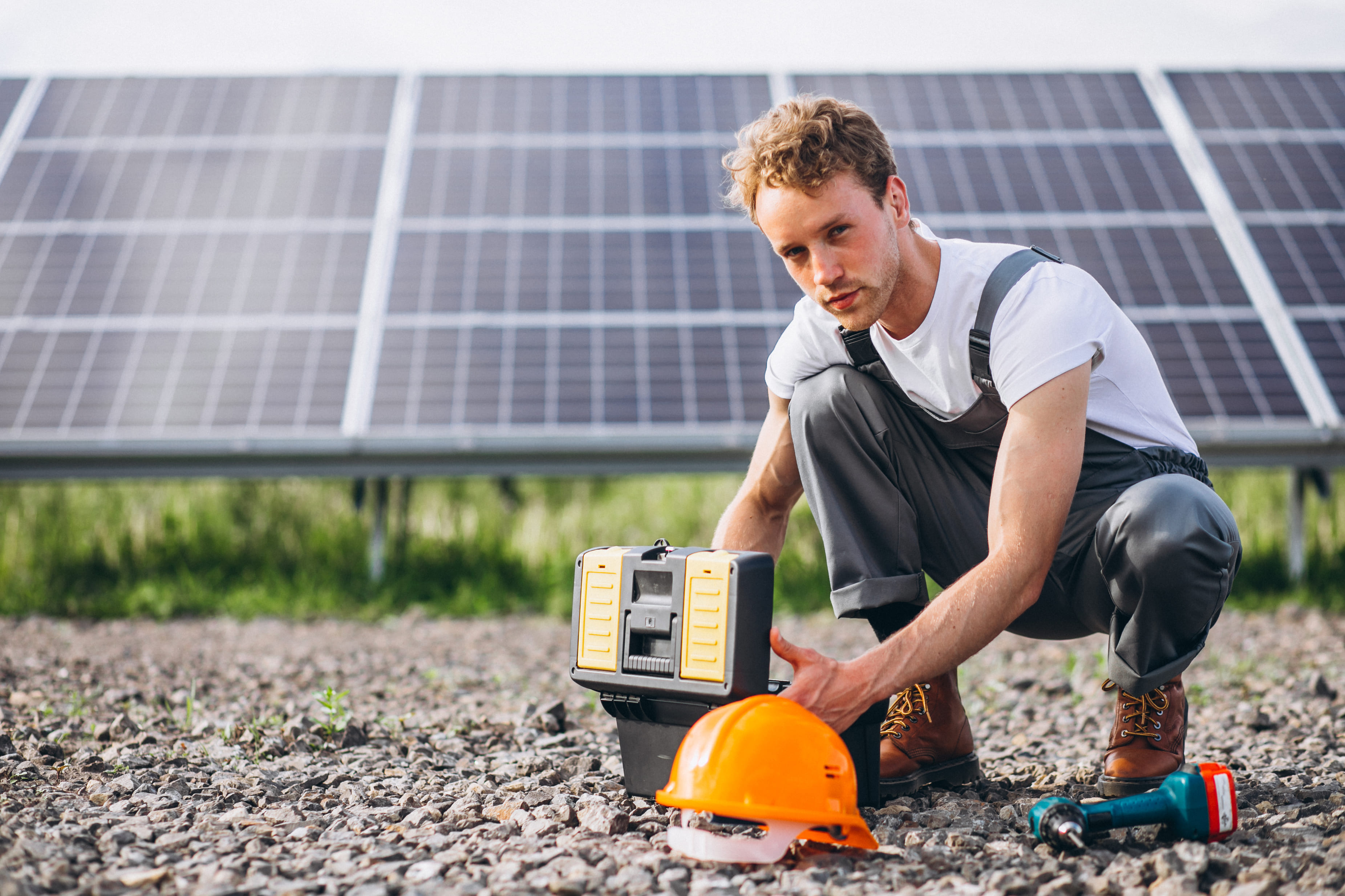Man worker in the field by the solar panels