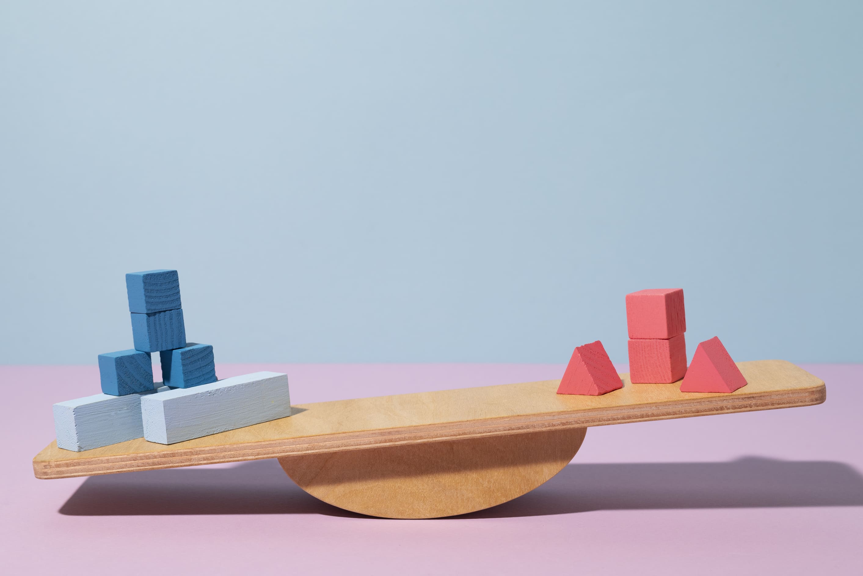 Wooden seesaw balances blue and red blocks