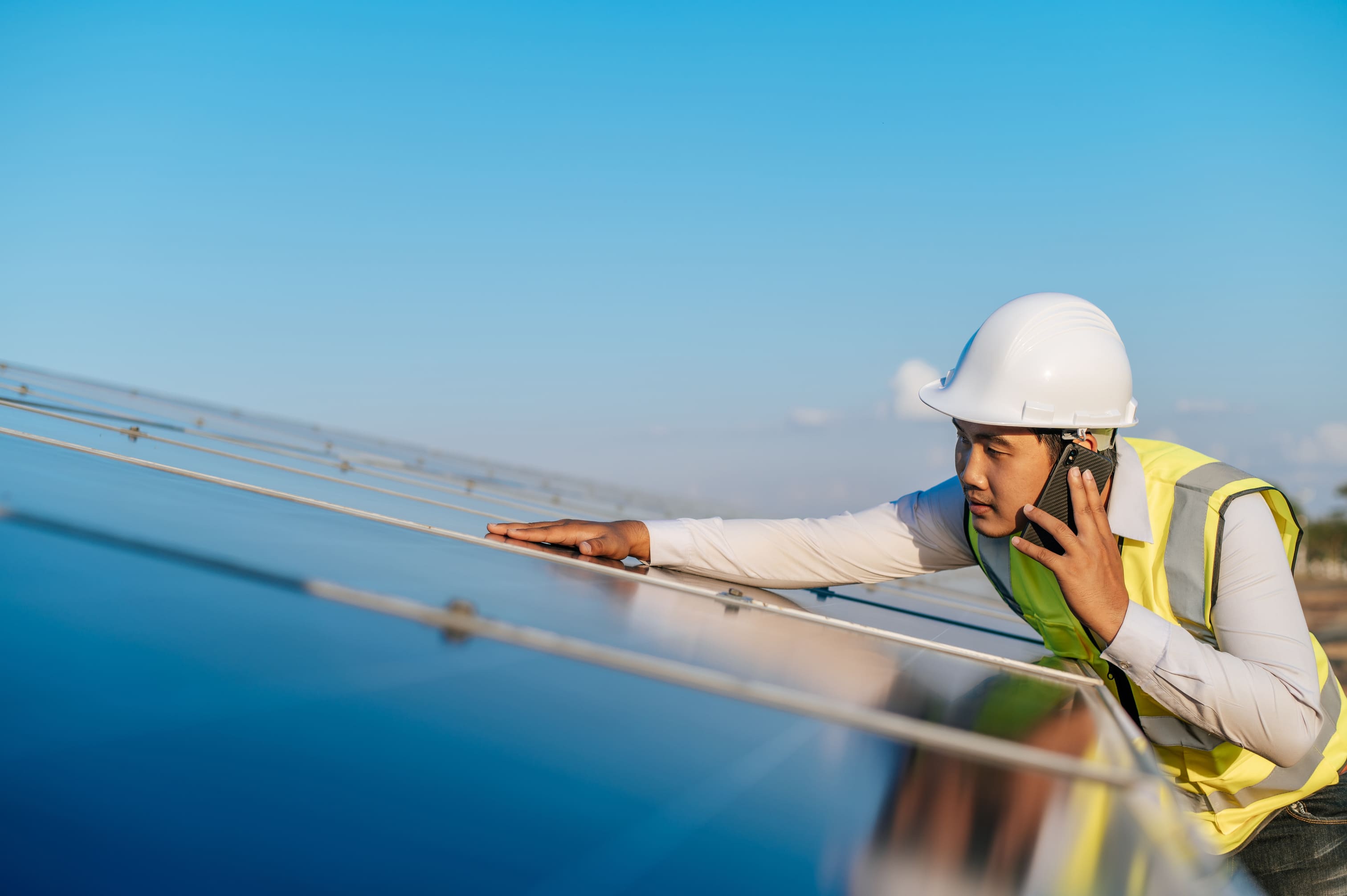Engineer inspects photovoltaic panel while on a call
