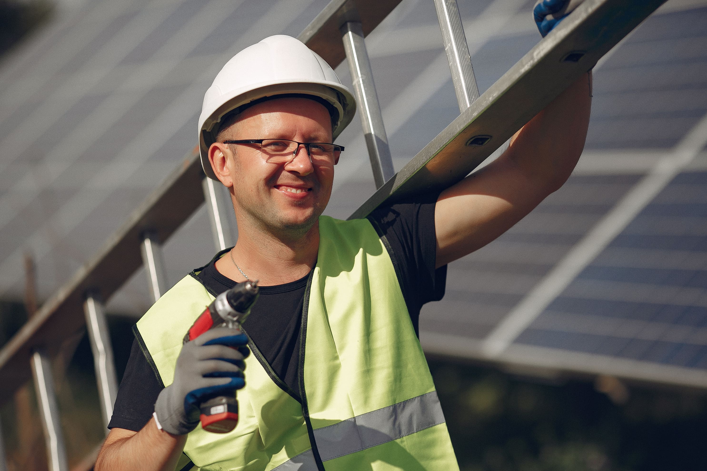 Smiling worker holds a drill and a ladder
