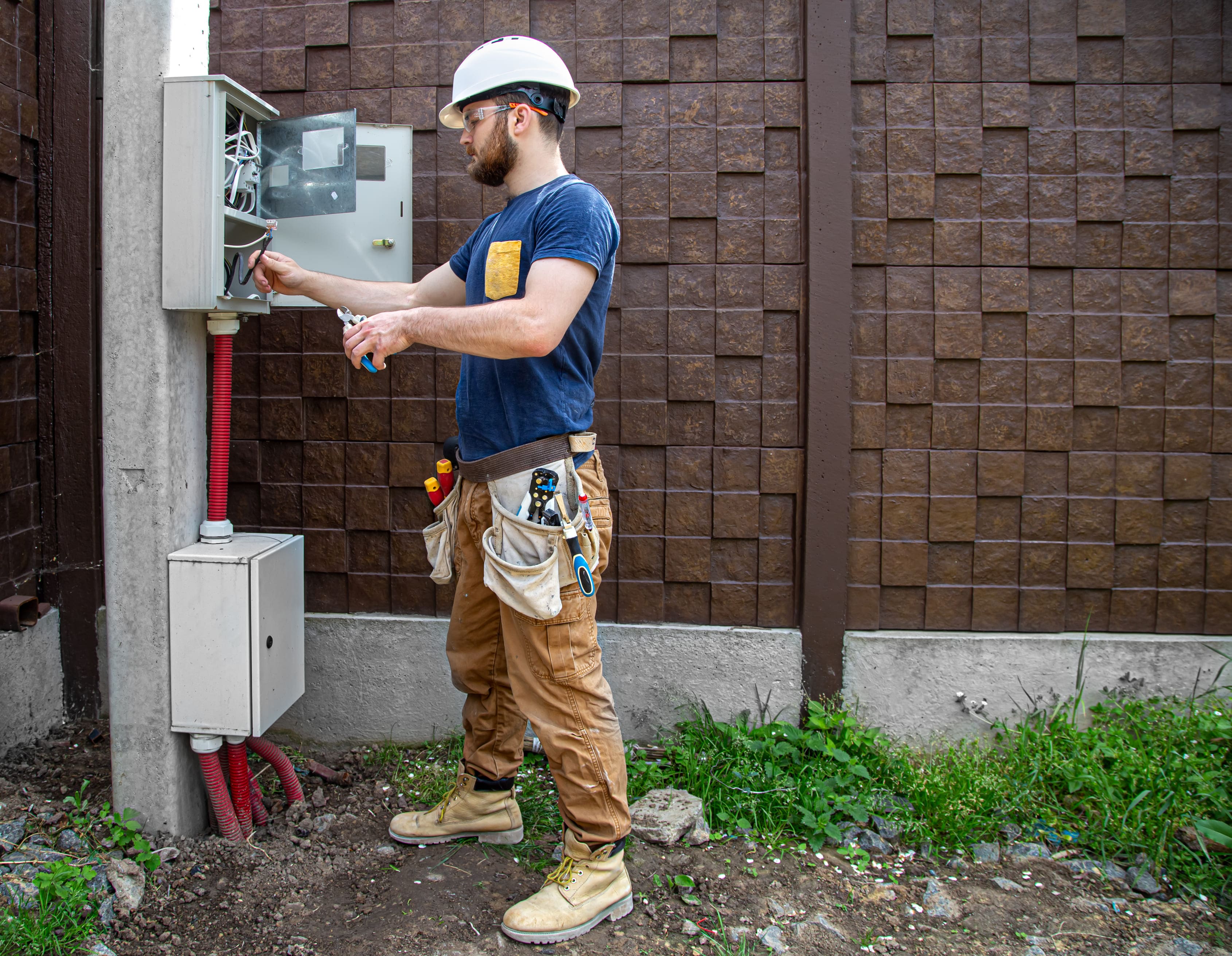 An electrician works on an outdoor switch box