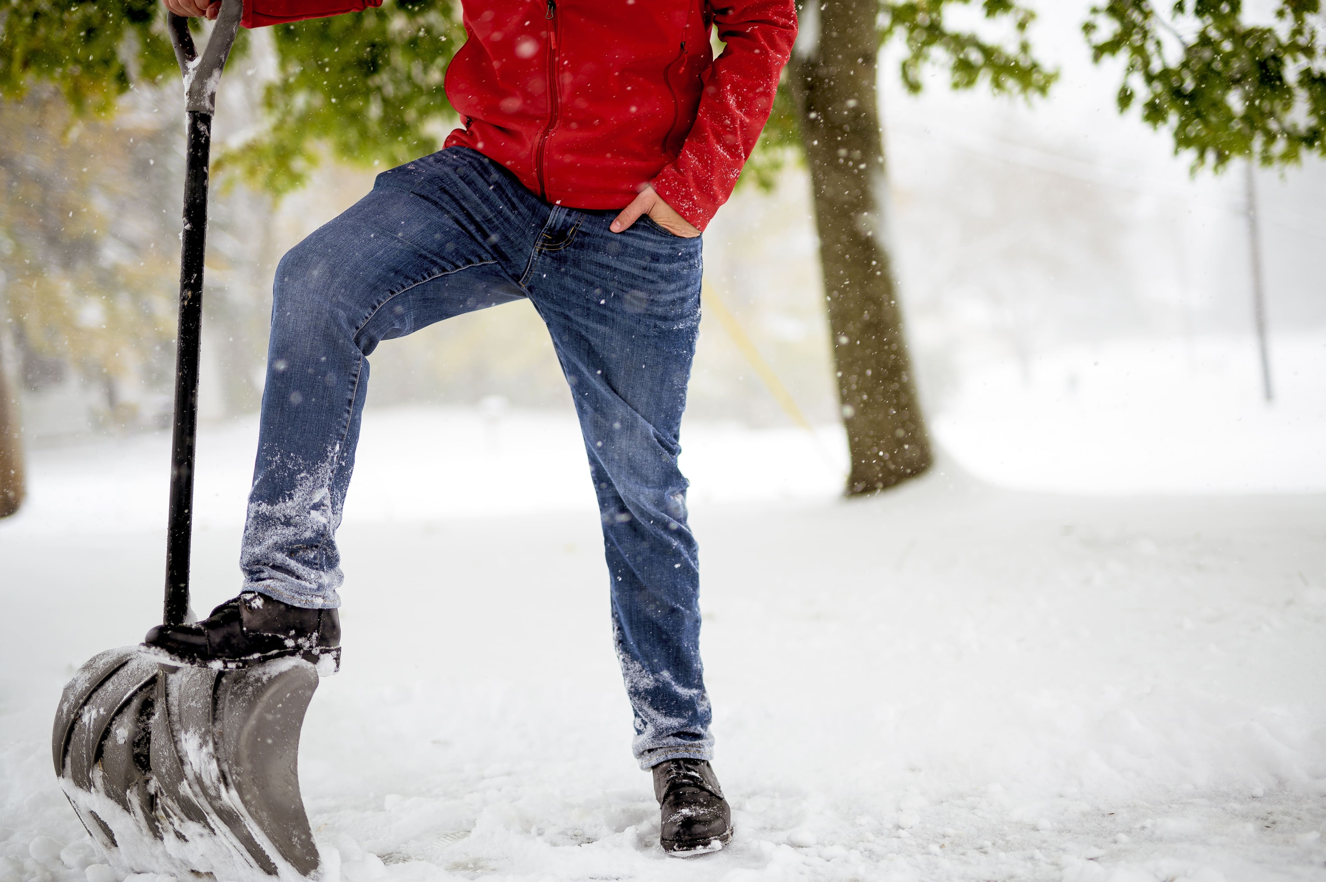 Closeup shot of a male with his foot on the snow shovel
