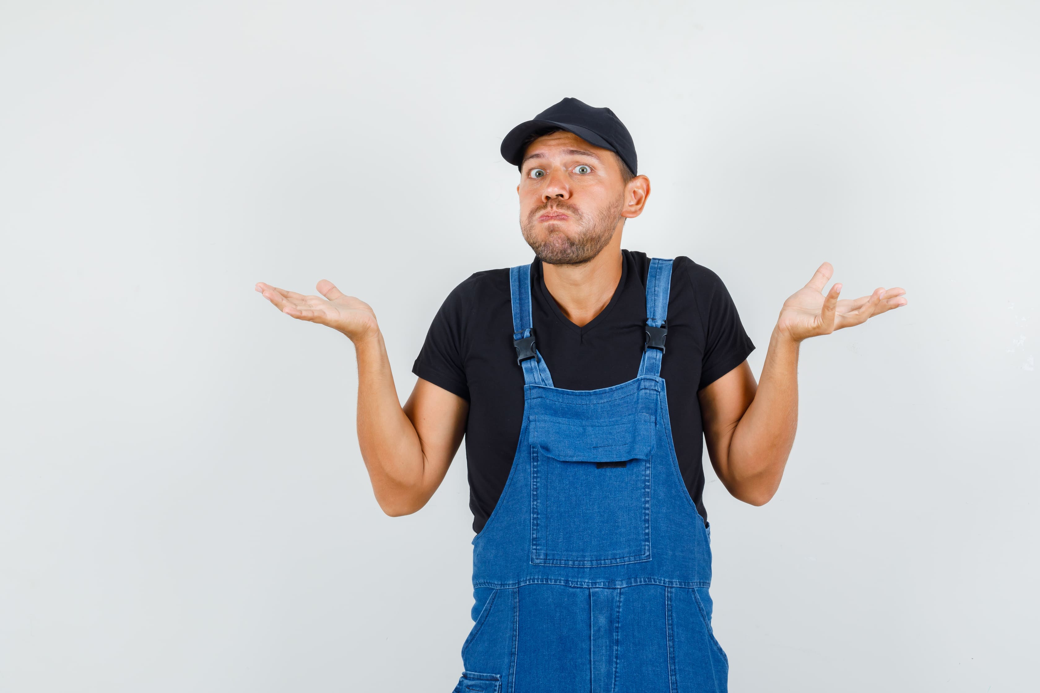 Mechanic in overalls shrugs with helpless gesture
