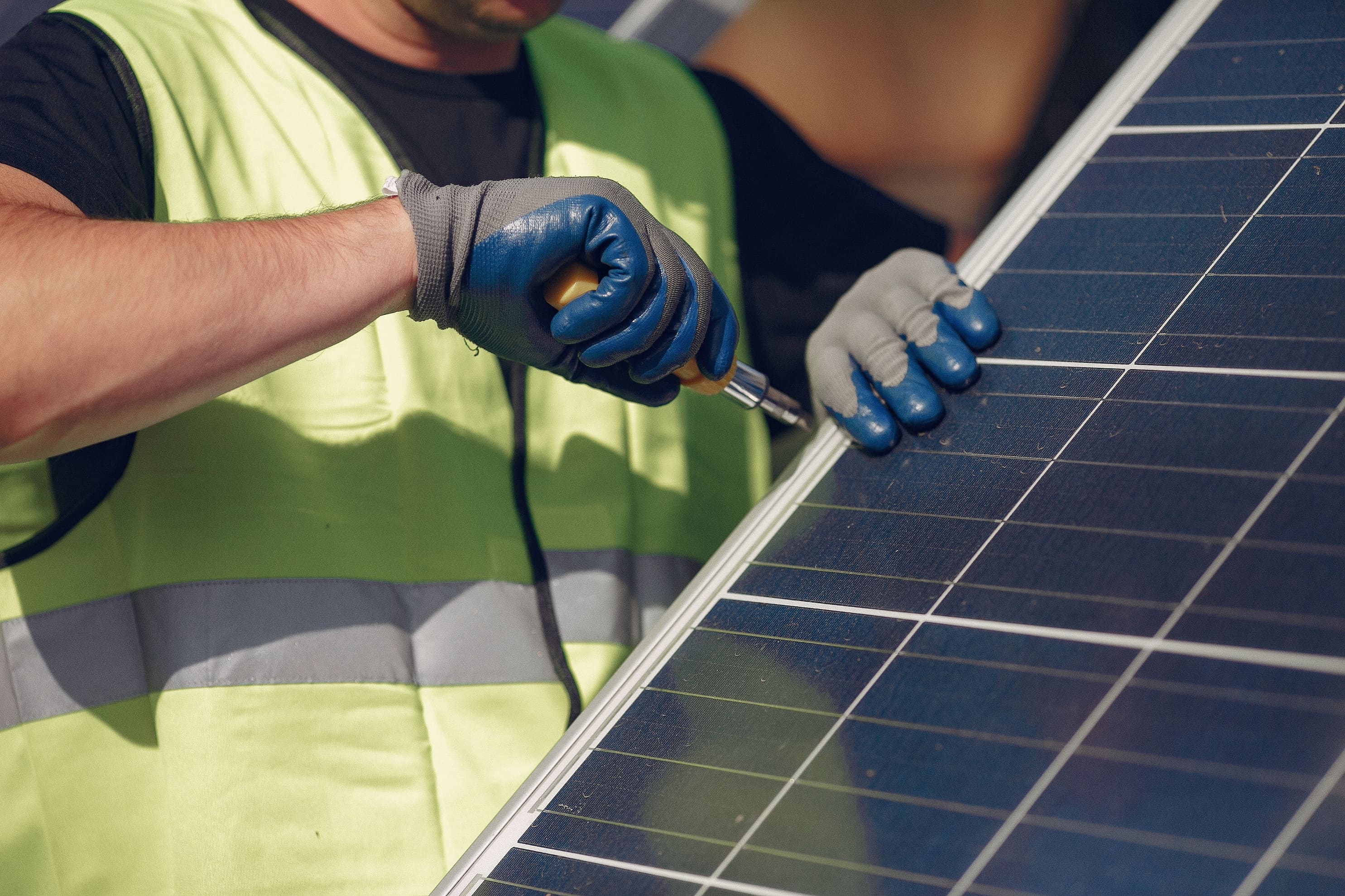 Worker installs a solar panel using a screwdriver