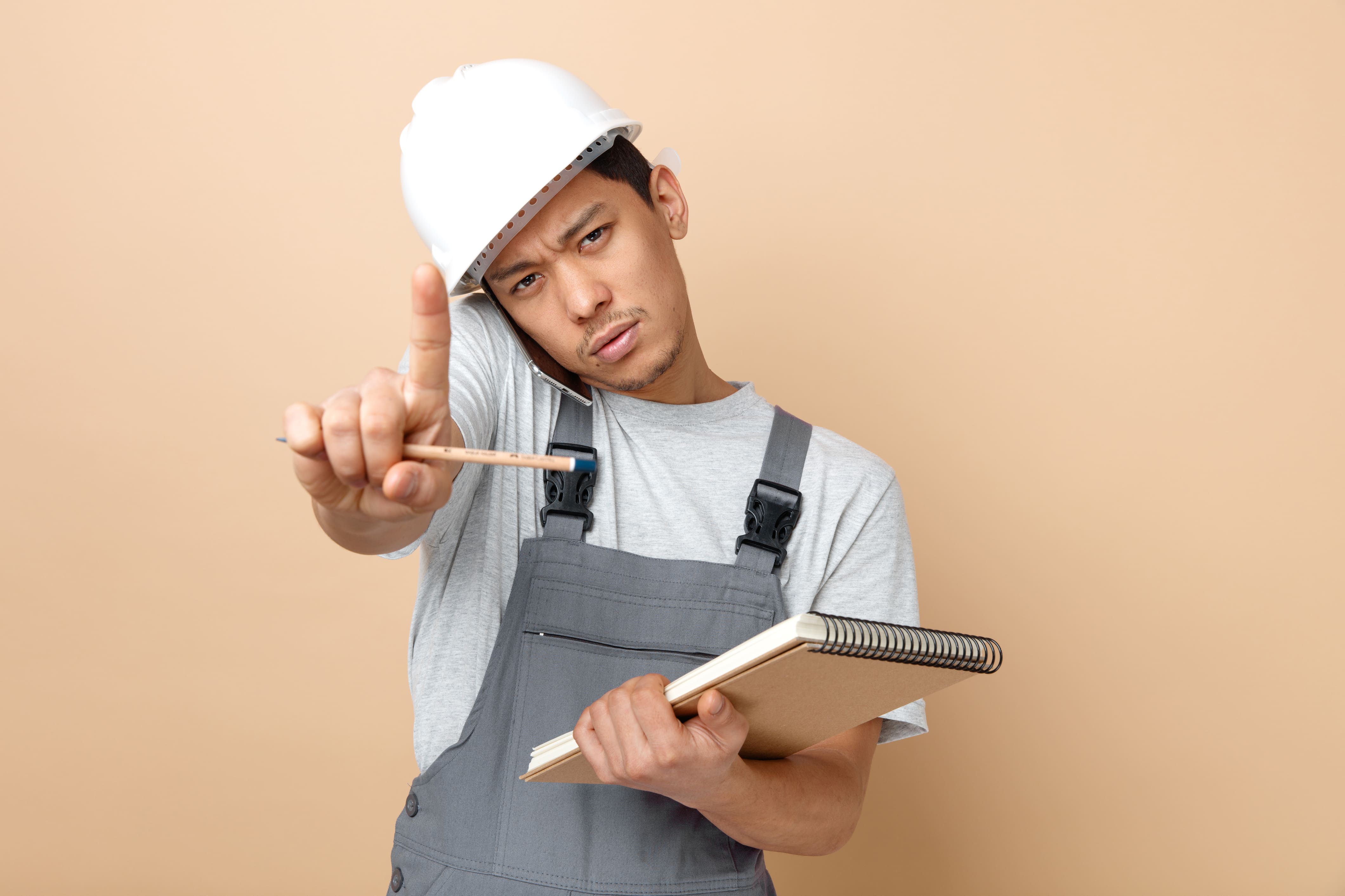 Young contractor wearing hard hat holding notepad