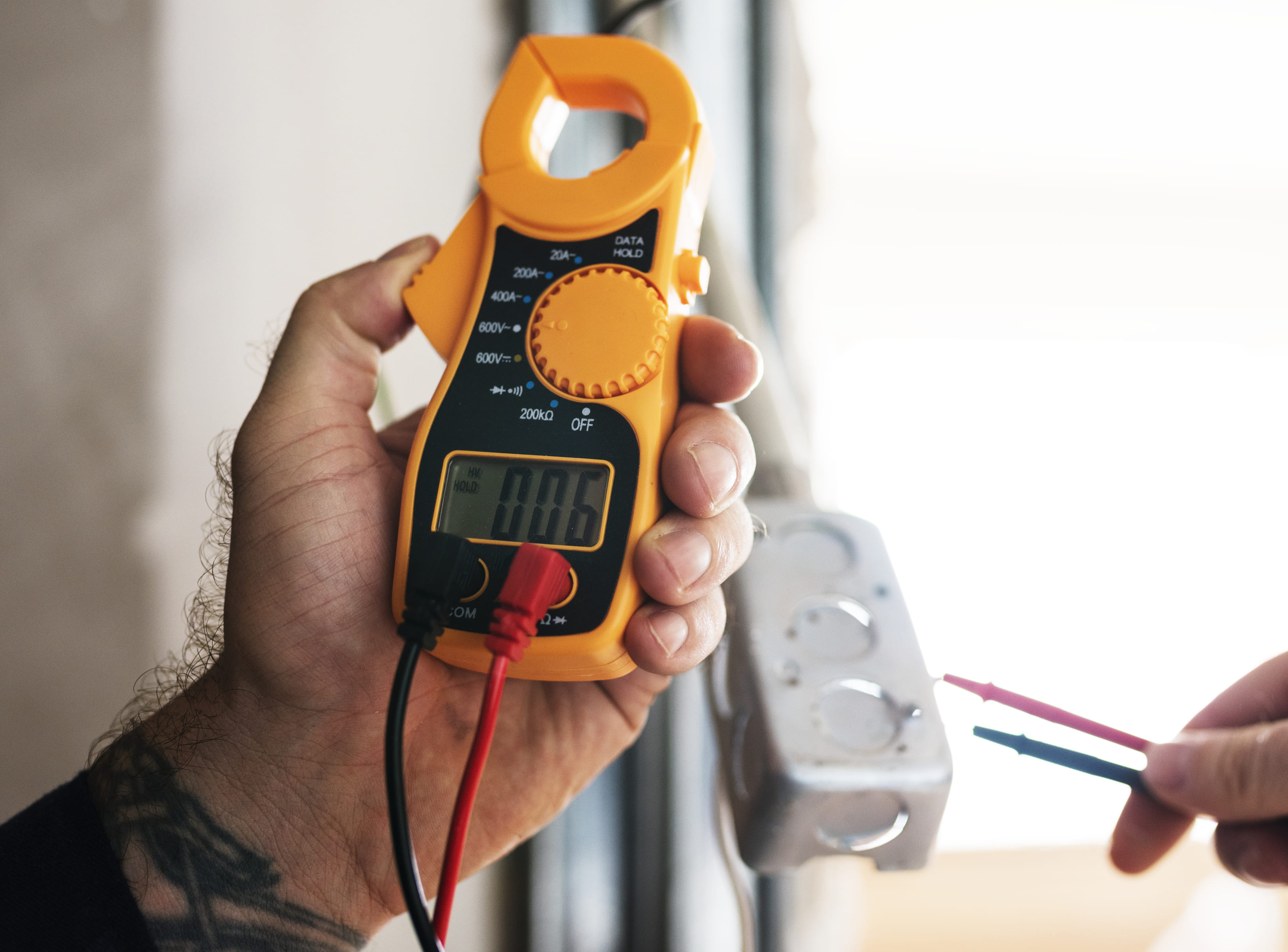 Electrician safely testing voltage with clamp multimeter tool
