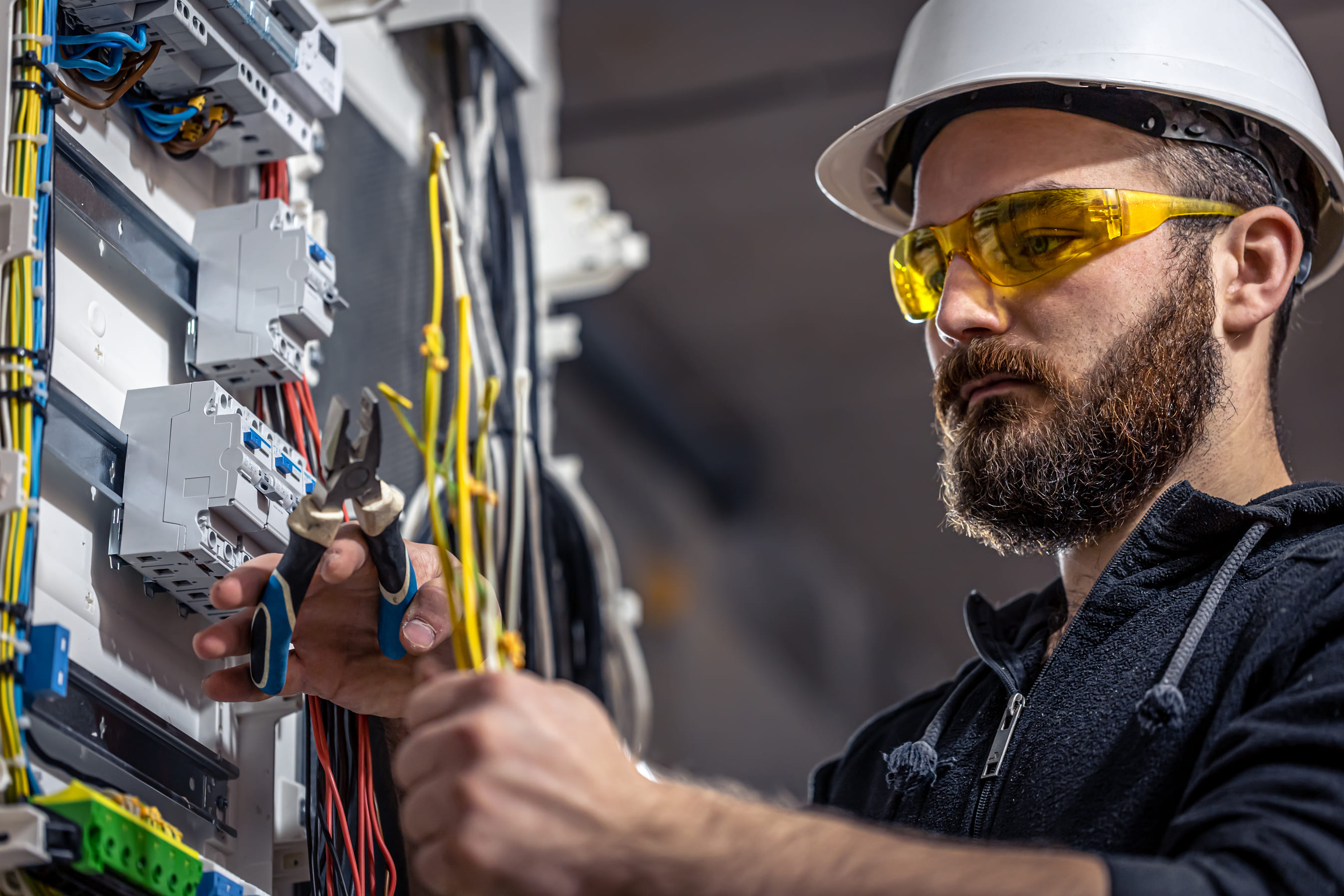 A male electrician works in a switchboard