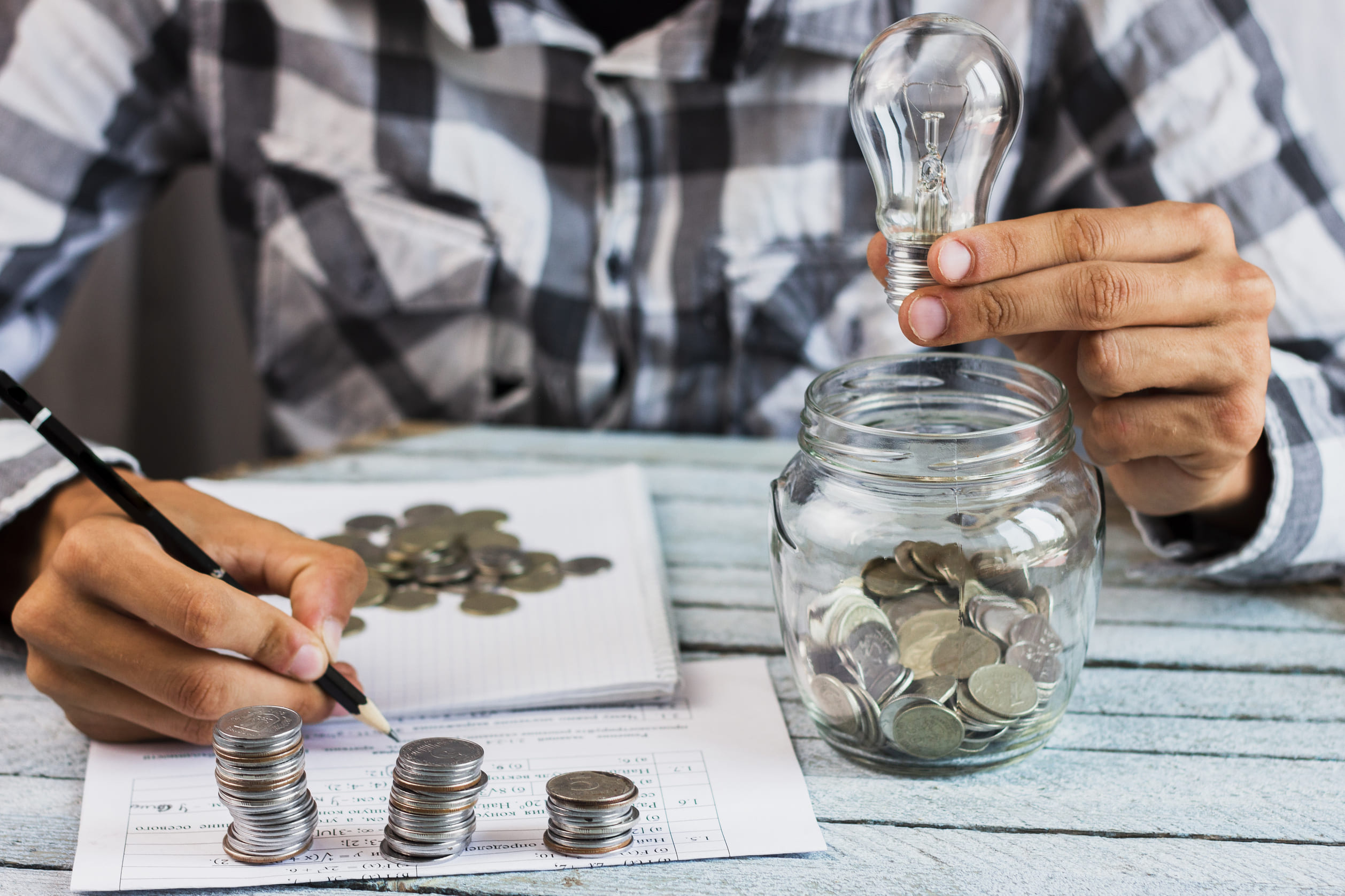 Man calculating savings holding a lightbulb and coins