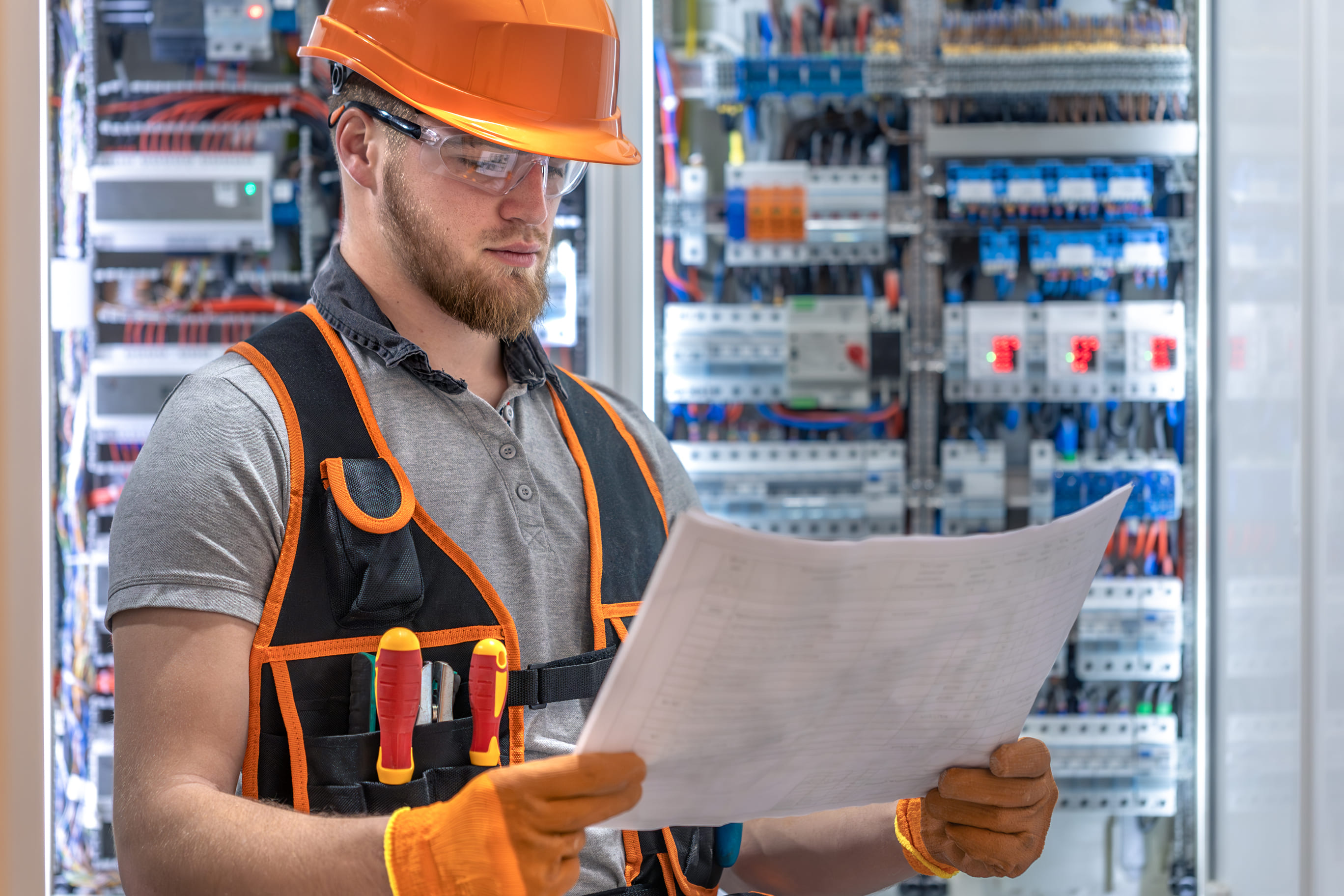 Electrician reviews blueprints near industrial switchboard