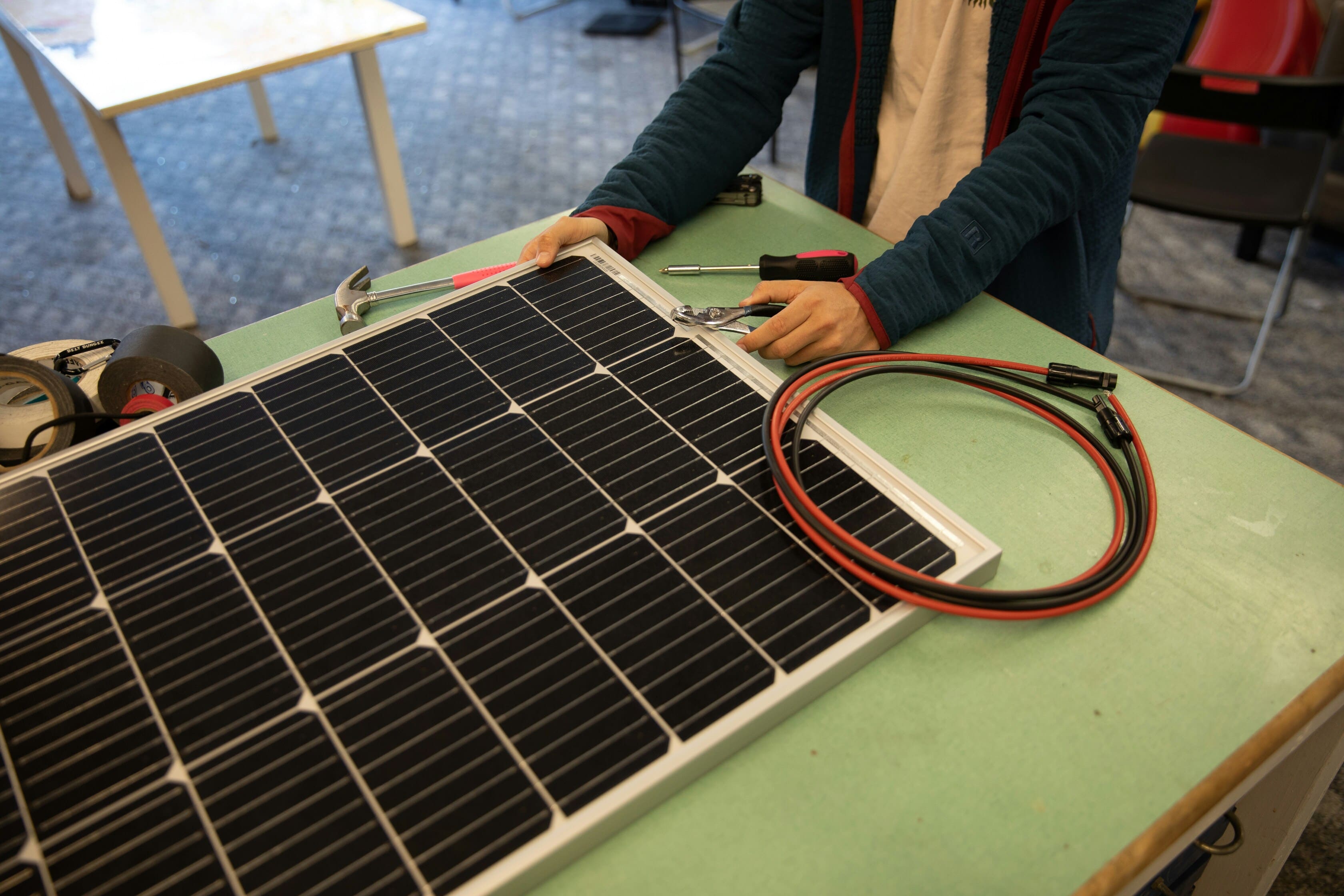 Worker assembles solar panel with tools and wires