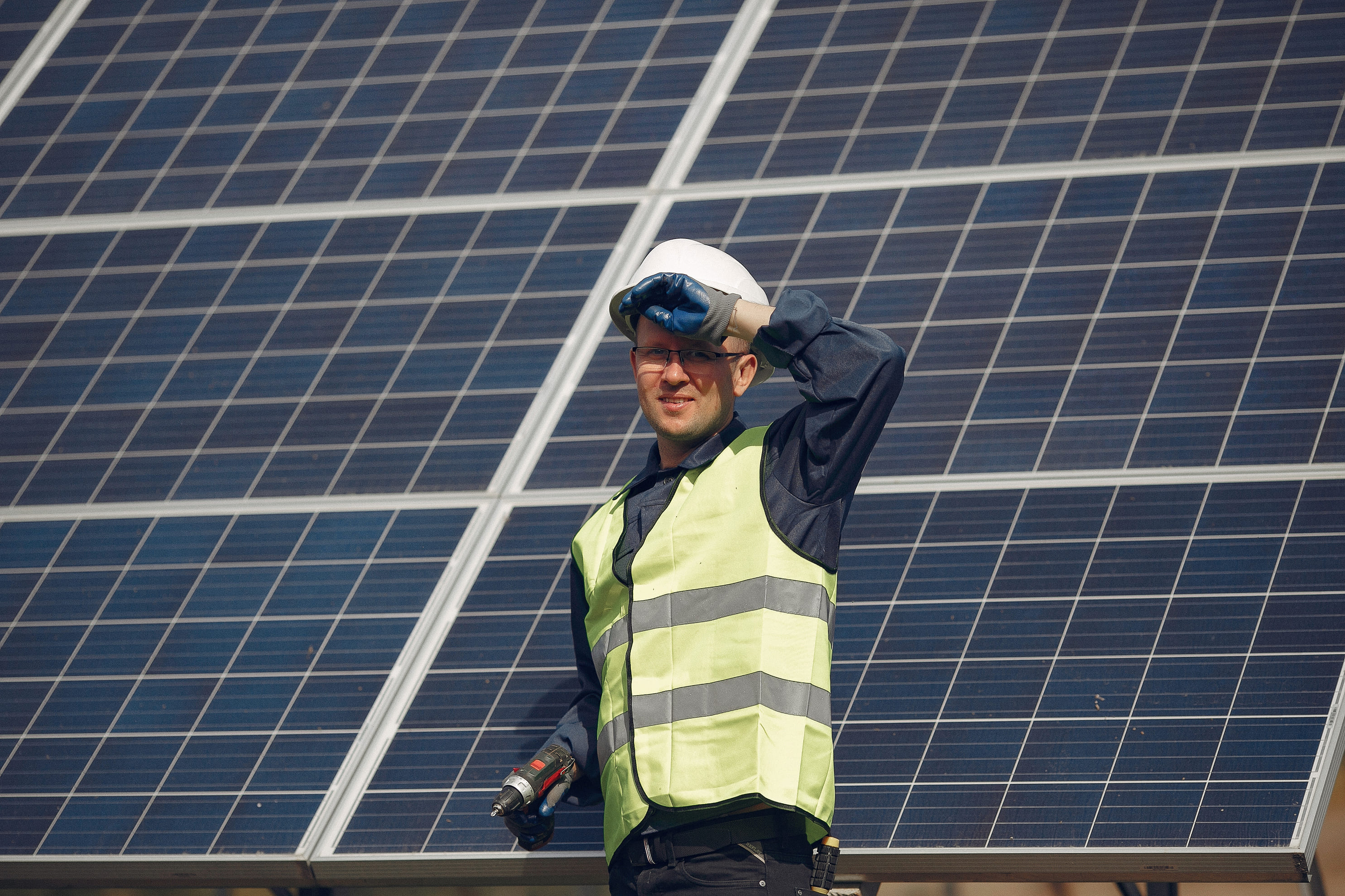 Worker shields eyes in front of solar panels