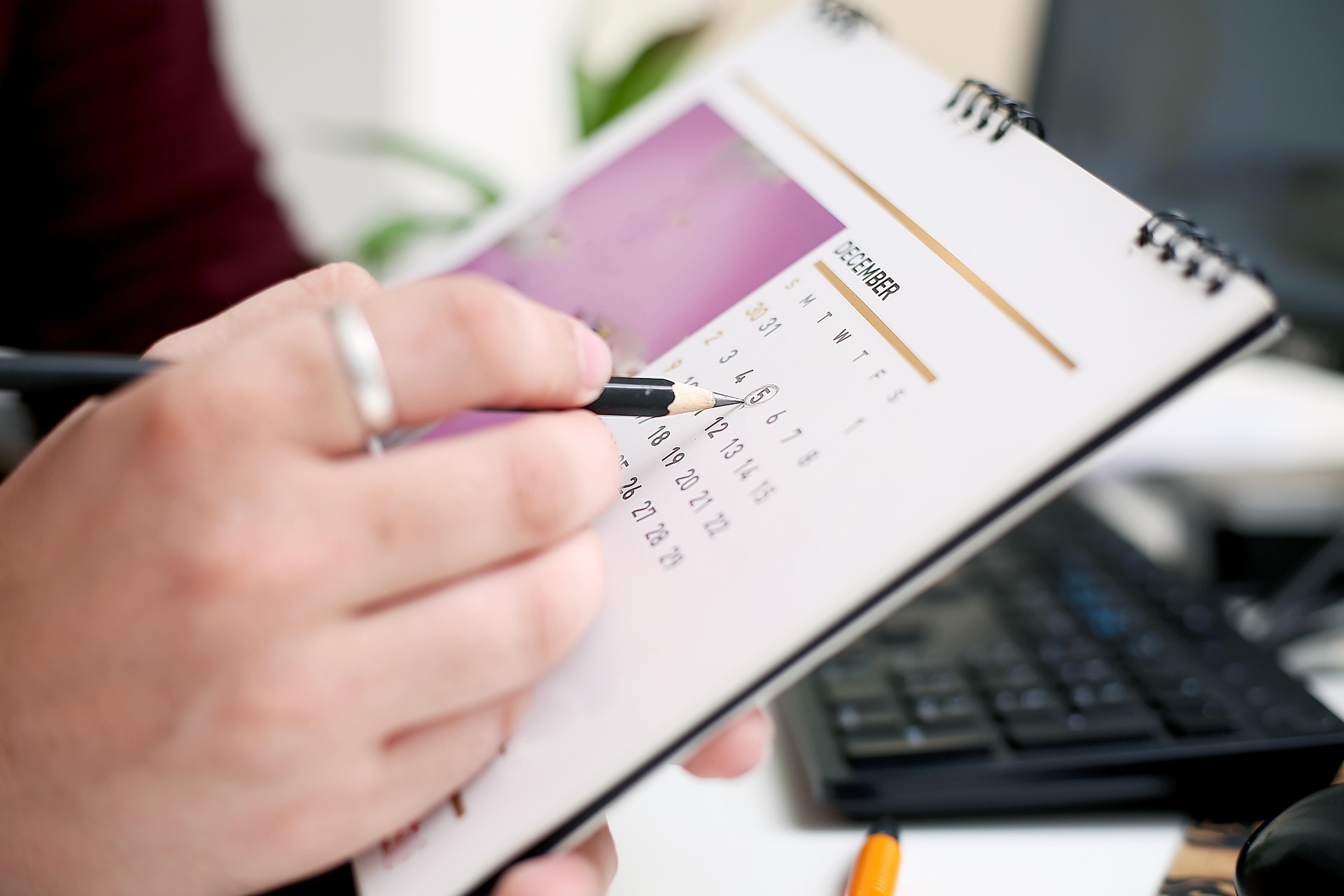 Hand circles date on a physical desktop calendar