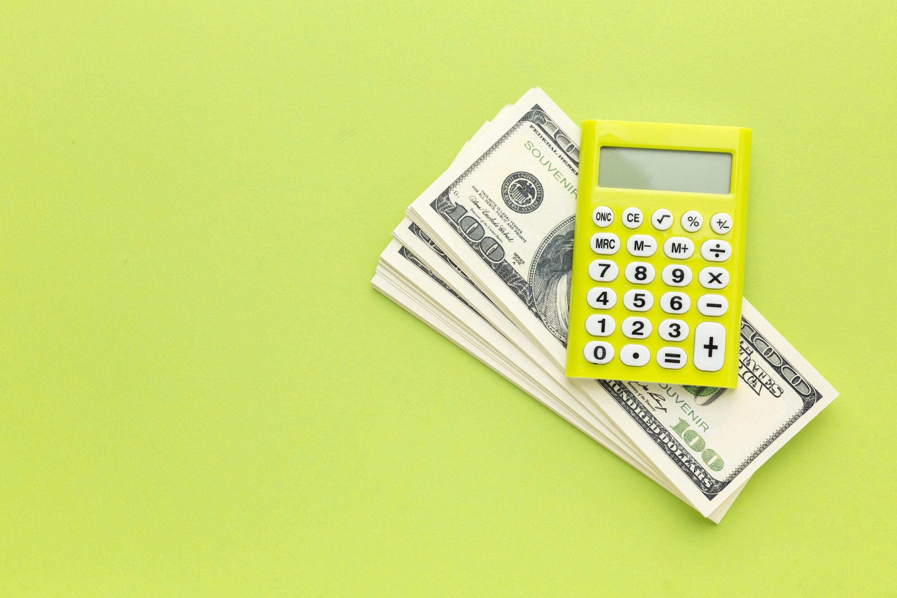 Yellow calculator sits on a stack of cash