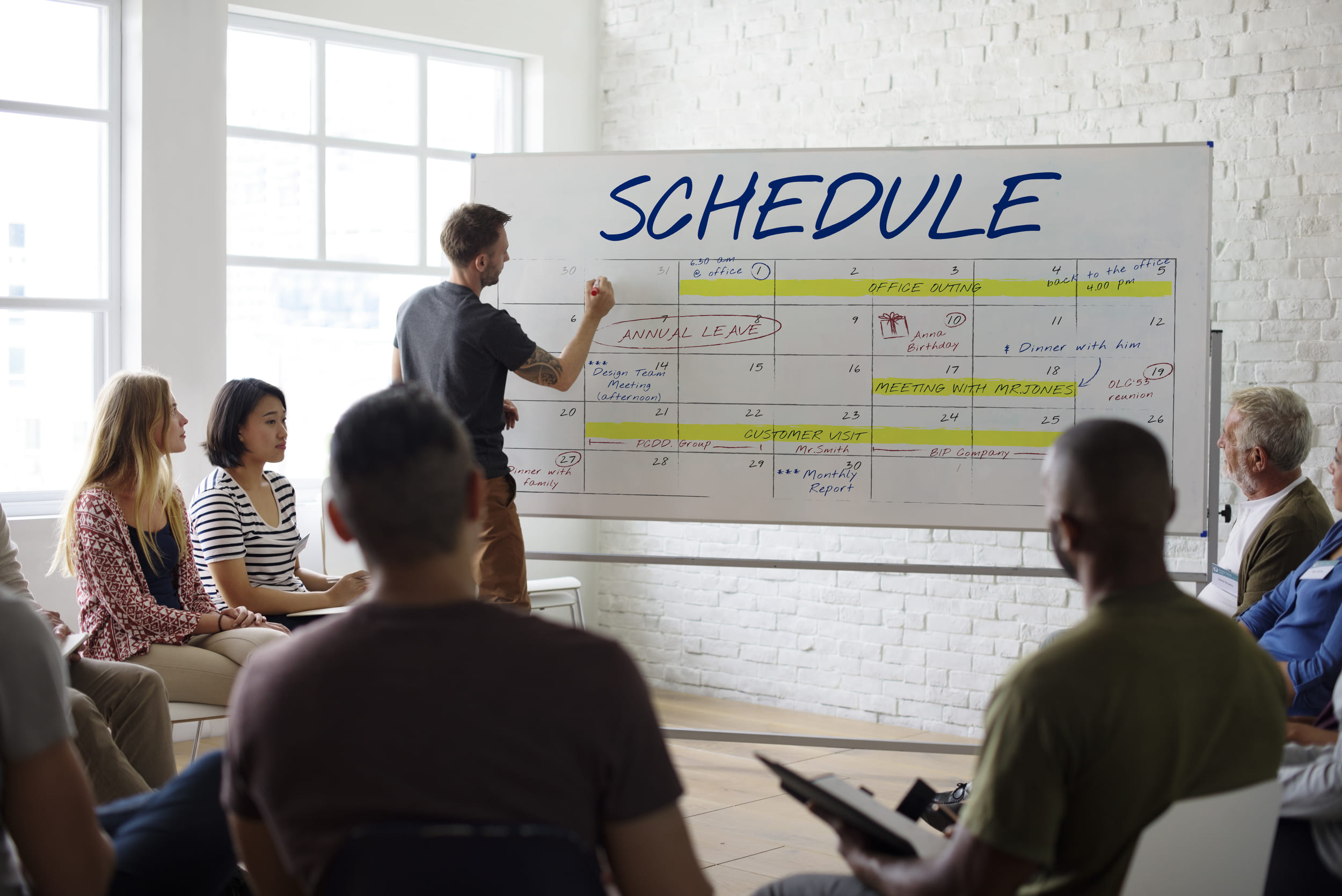Man writes project schedule on large whiteboard