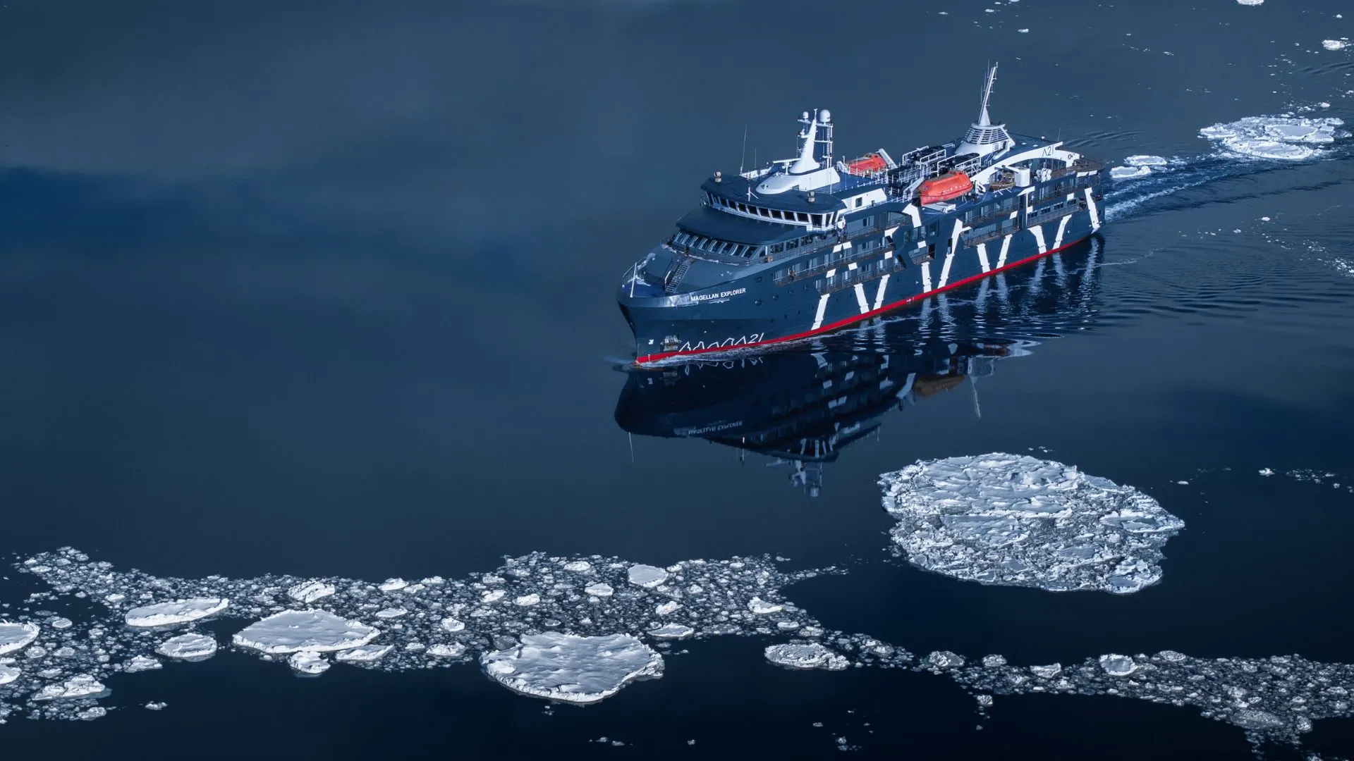 The cruise ship Magellan Explorer sailing through icy Arctic waters with floating ice chunks.
