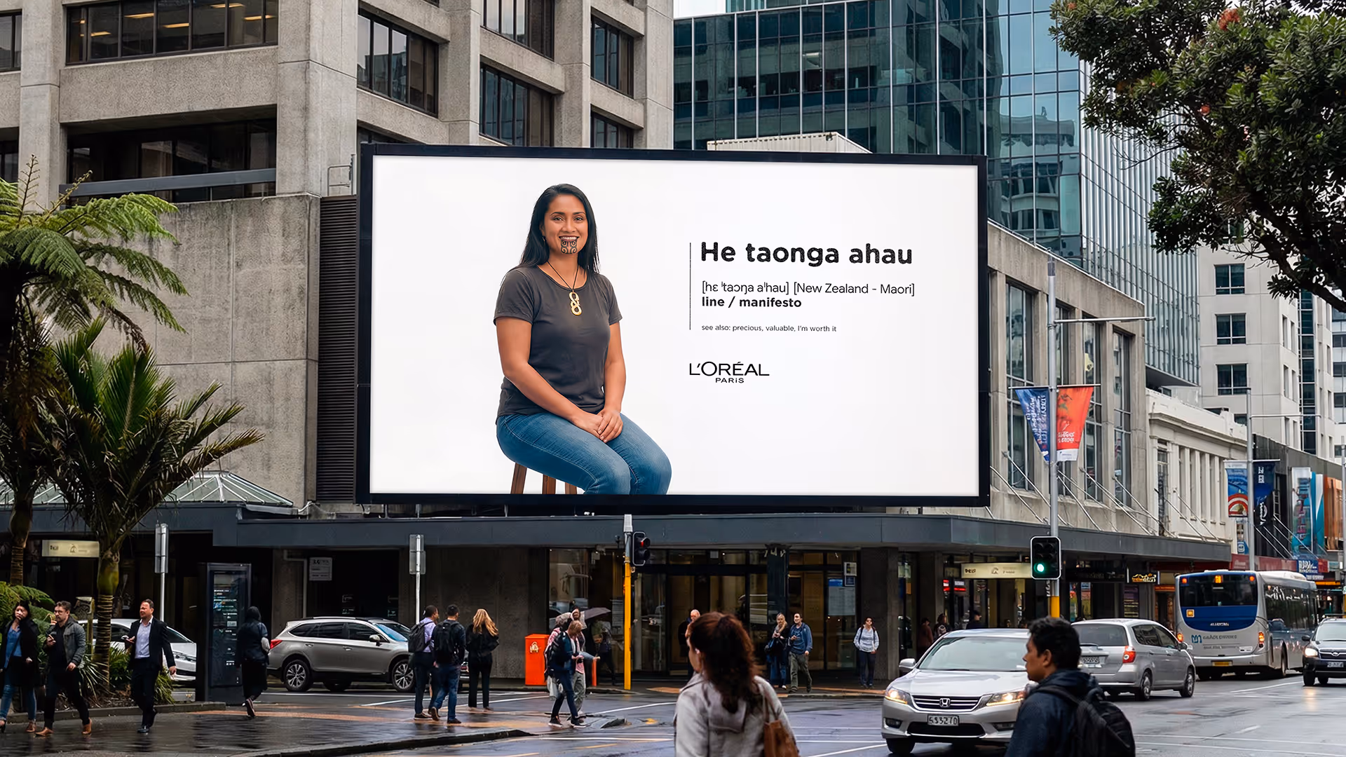Billboard in a city featuring a seated woman with a traditional Maori chin tattoo and text explaining the Maori phrase 'He taonga ahau' meaning line or manifesto, with L'Oréal Paris branding.