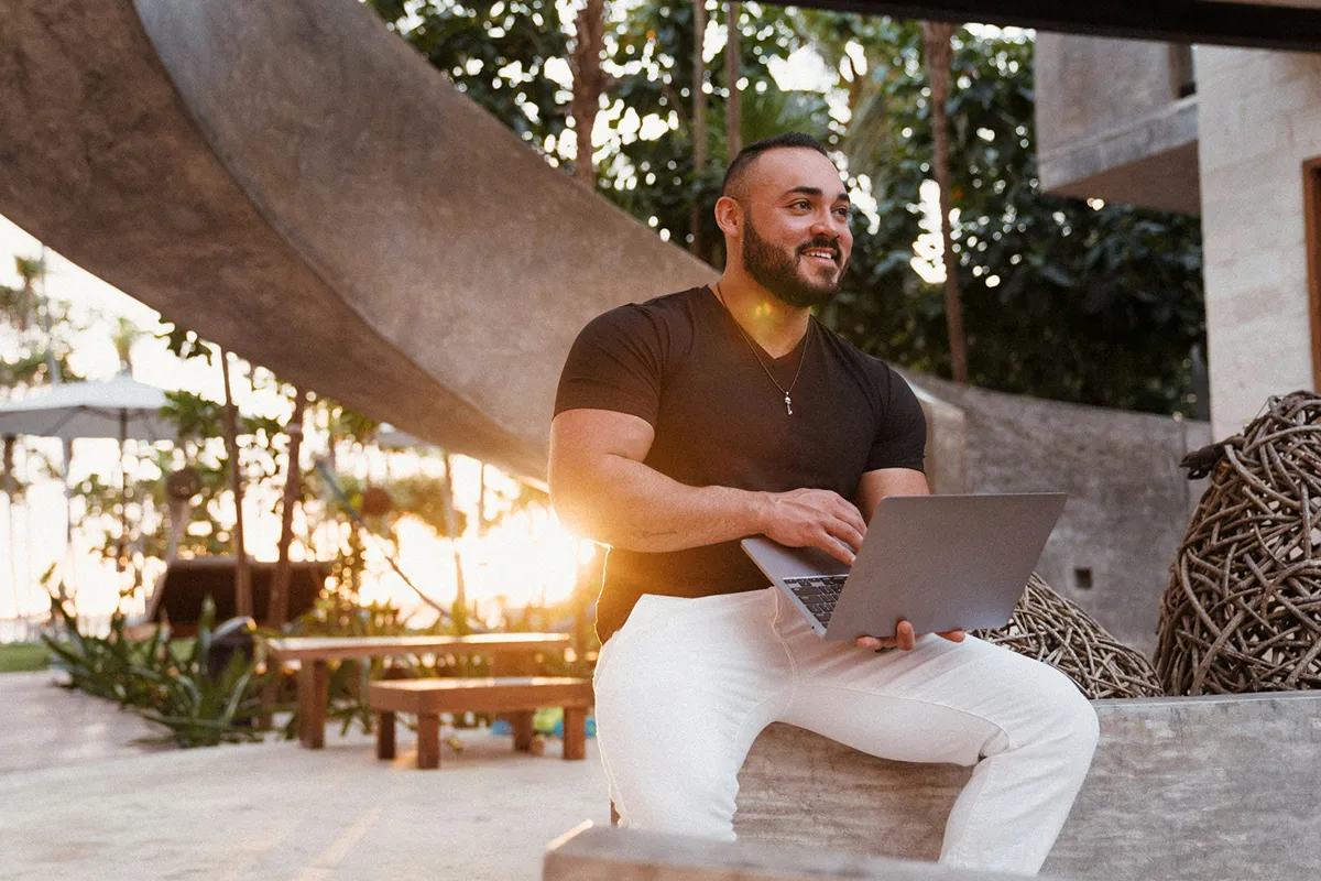 A man sitting with his laptop open on his lap while outside