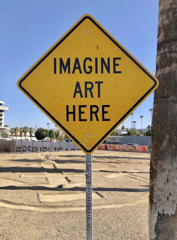On the grounds of the Palm Springs Museum of Art. A yellow sign that reads "Imagine art here"