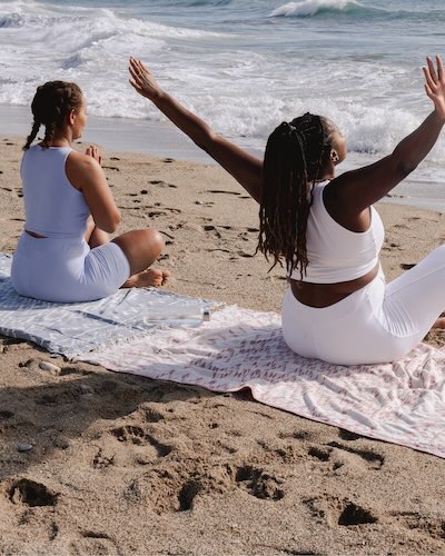 Woman sitting on beach stretching