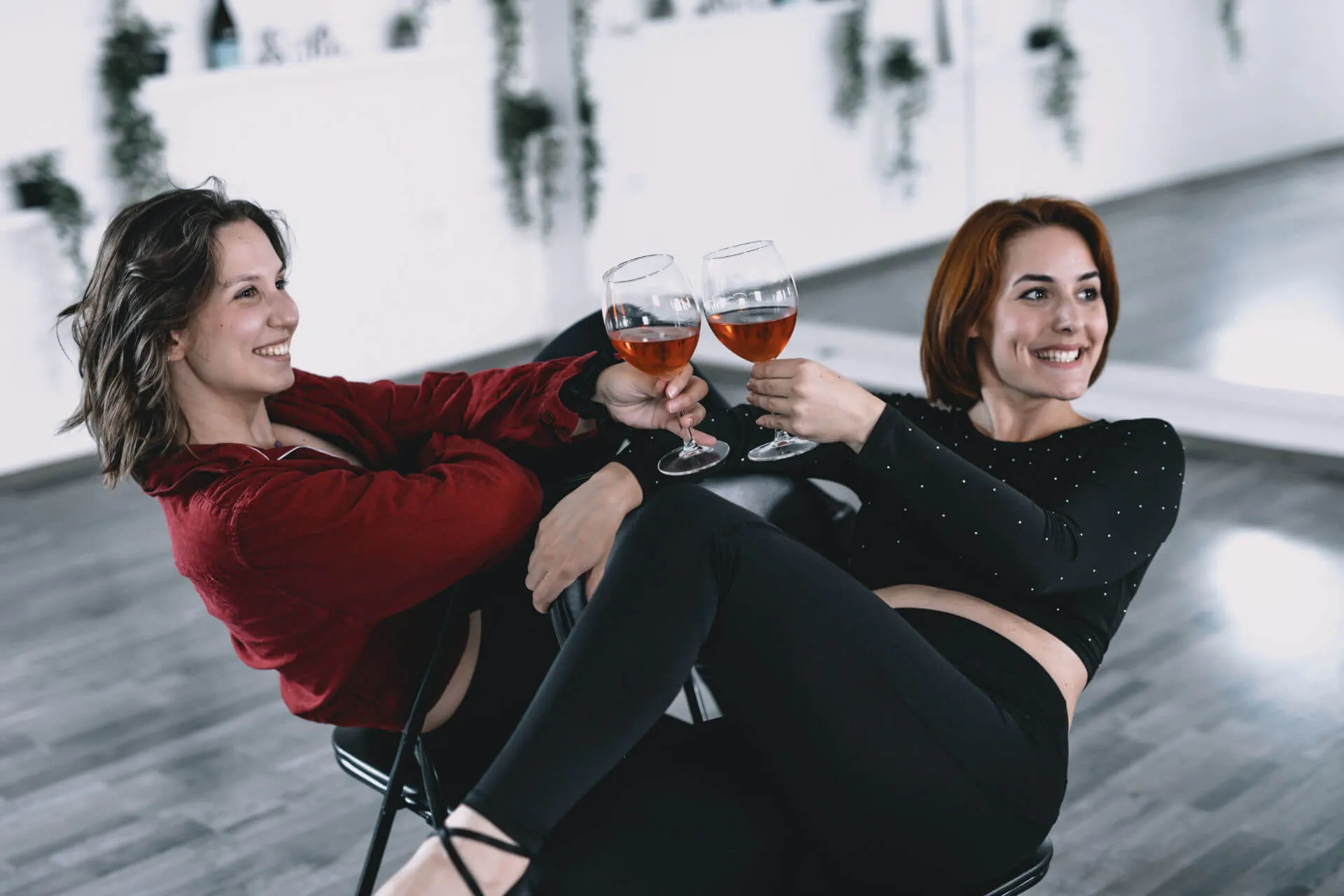 Dvije žene poziraju na stolicama sa čašama vina