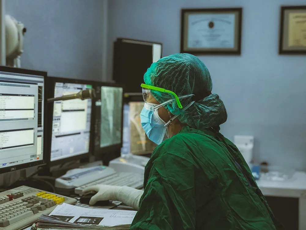 Clinician monitoring multiple connected screens in a hospital control room