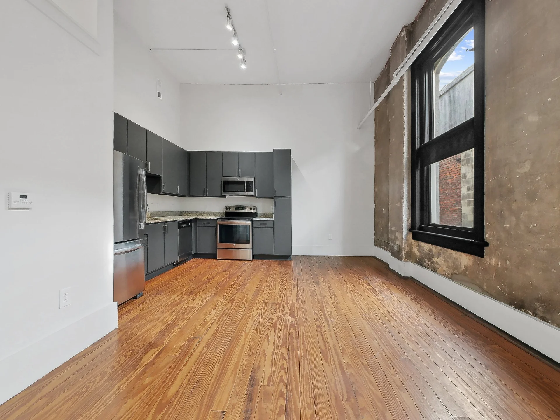 Open floor plan with kitchen and living area featuring exposed brick