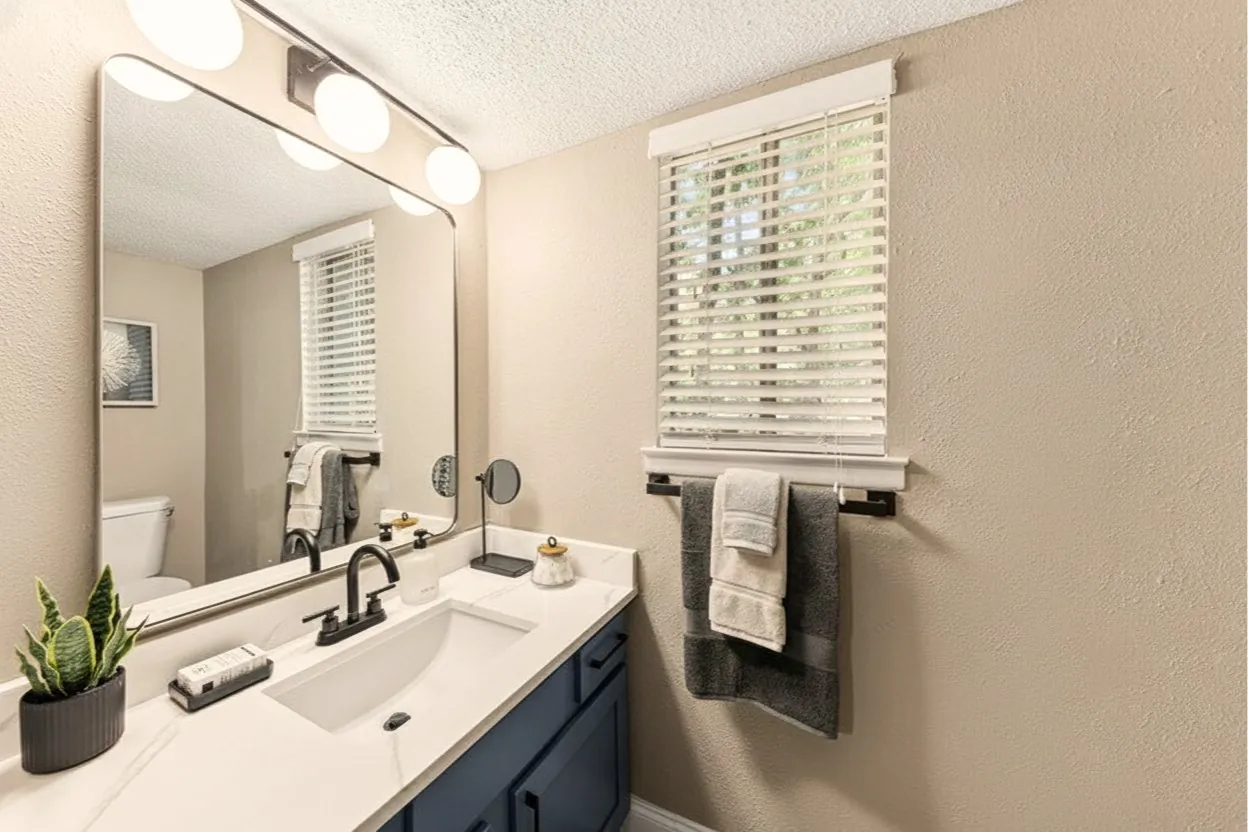 Styled bathroom with navy vanity and window at The Kenzie