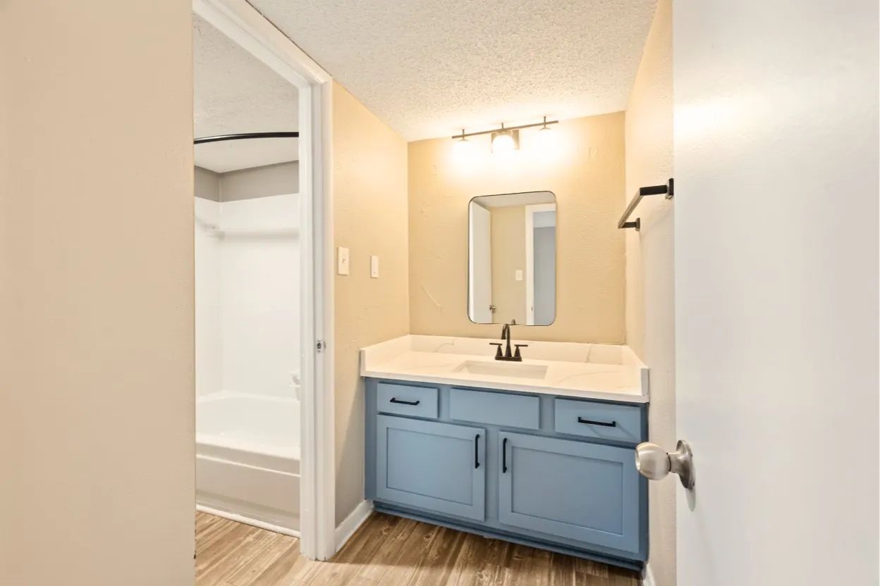 Bathroom with blue vanity and warm lighting at The Kenzie