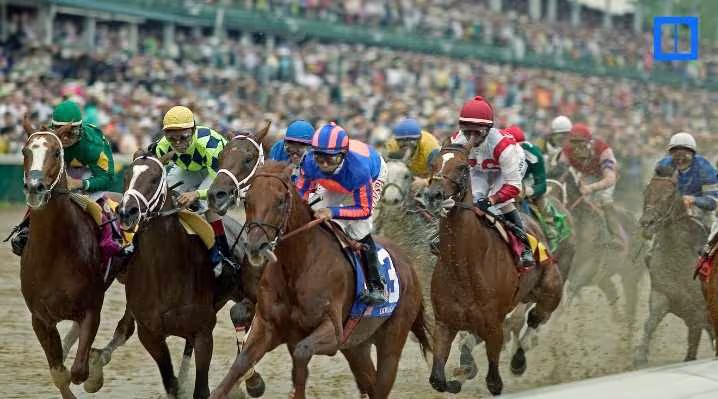 A group of jockeys in colorful silks racing thoroughbred horses around a dirt track bend during the Kentucky Derby with a crowded grandstand in the background.