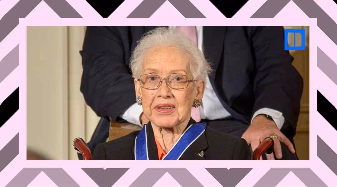 A close-up portrait of NASA mathematician Katherine Johnson wearing glasses and a blue Presidential Medal of Freedom ribbon. She is seated and smiling during an event.