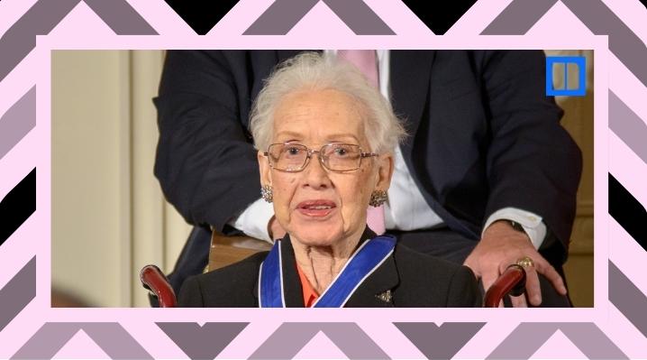 A close-up portrait of NASA mathematician Katherine Johnson wearing glasses and a blue Presidential Medal of Freedom ribbon. She is seated and smiling during an event.
