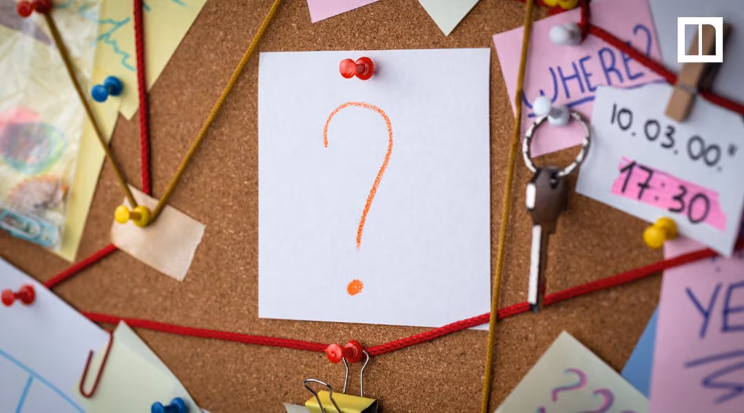 Corkboard with pinned notes, red string, and a paper showing an orange question mark.