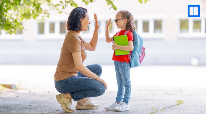 Parent and child high-five outside school, showing a welcoming start to back-to-school night.