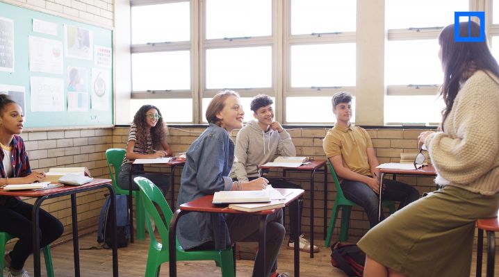 High school students in a classroom listening to a teacher during an elective social studies class discussion.