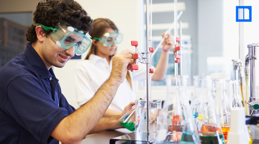 Students wearing safety goggles conduct a chemistry lab experiment for a hands-on science curriculum lesson.