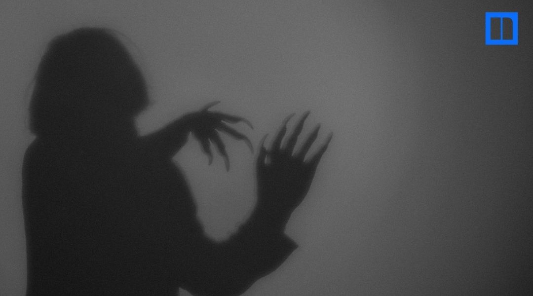 Shadowy figure with raised hands and long, clawlike fingers behind a translucent screen.
