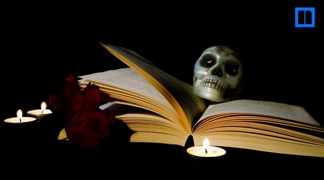 Open books, a small skull, and lit candles against a dark background.