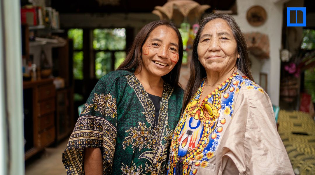 Two women wearing colorful patterned clothing stand together indoors, featured in a Native American Heritage Month STEM education blog.