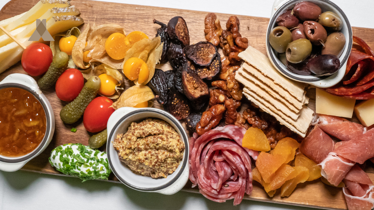 Assorted meats, cheeses, olives, and bread on wooden board — Corazón by Baires charcuterie platter spread.