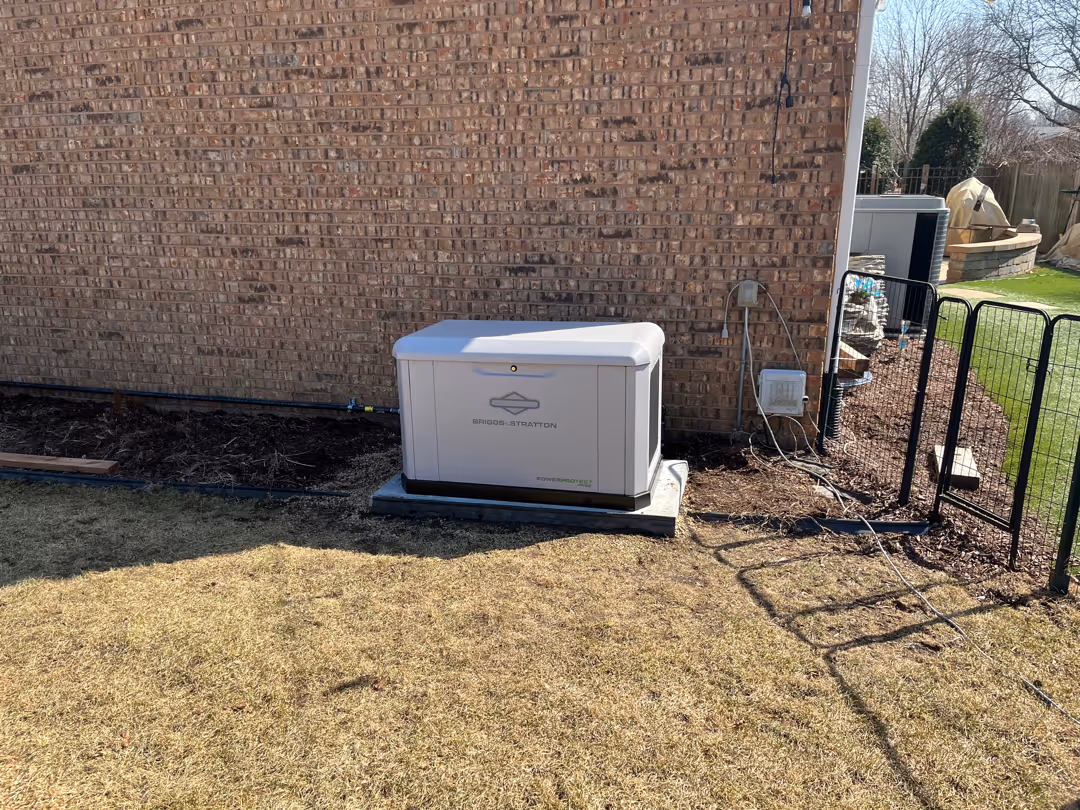 Briggs & Stratton standby generator installed on a concrete pad next to a brick house in a backyard.