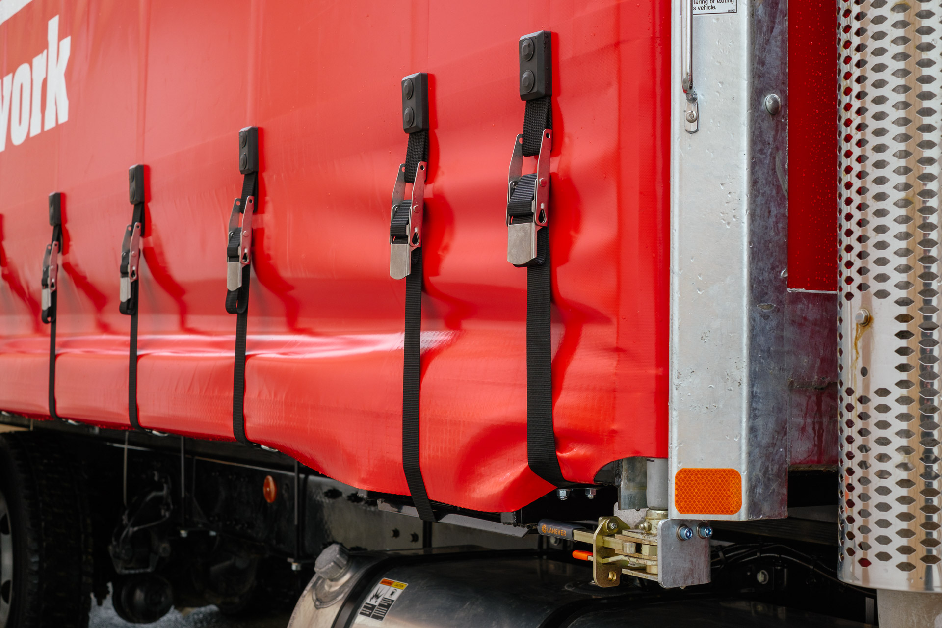 Close up detail of the ratchet tensioners and straps for the retractable curtain on a curtainside body.