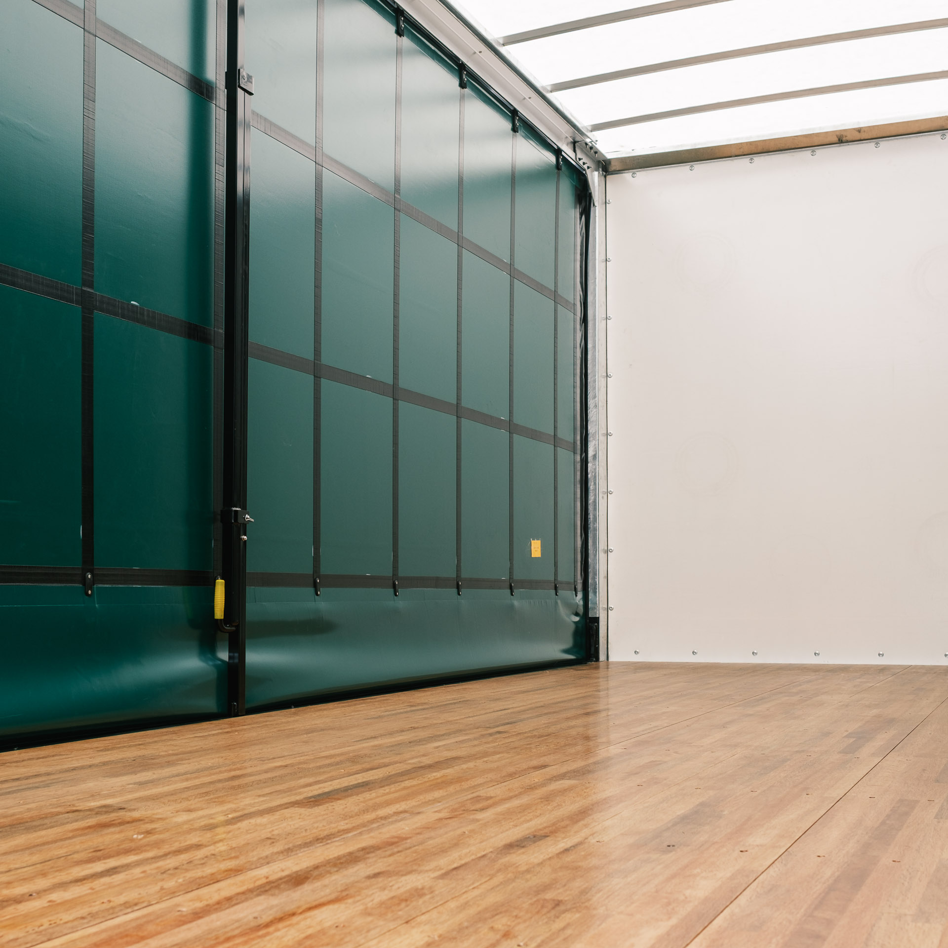 Inside a curtainside truck with the curtains closed. This truck has a translucent roof and smooth polished floors.