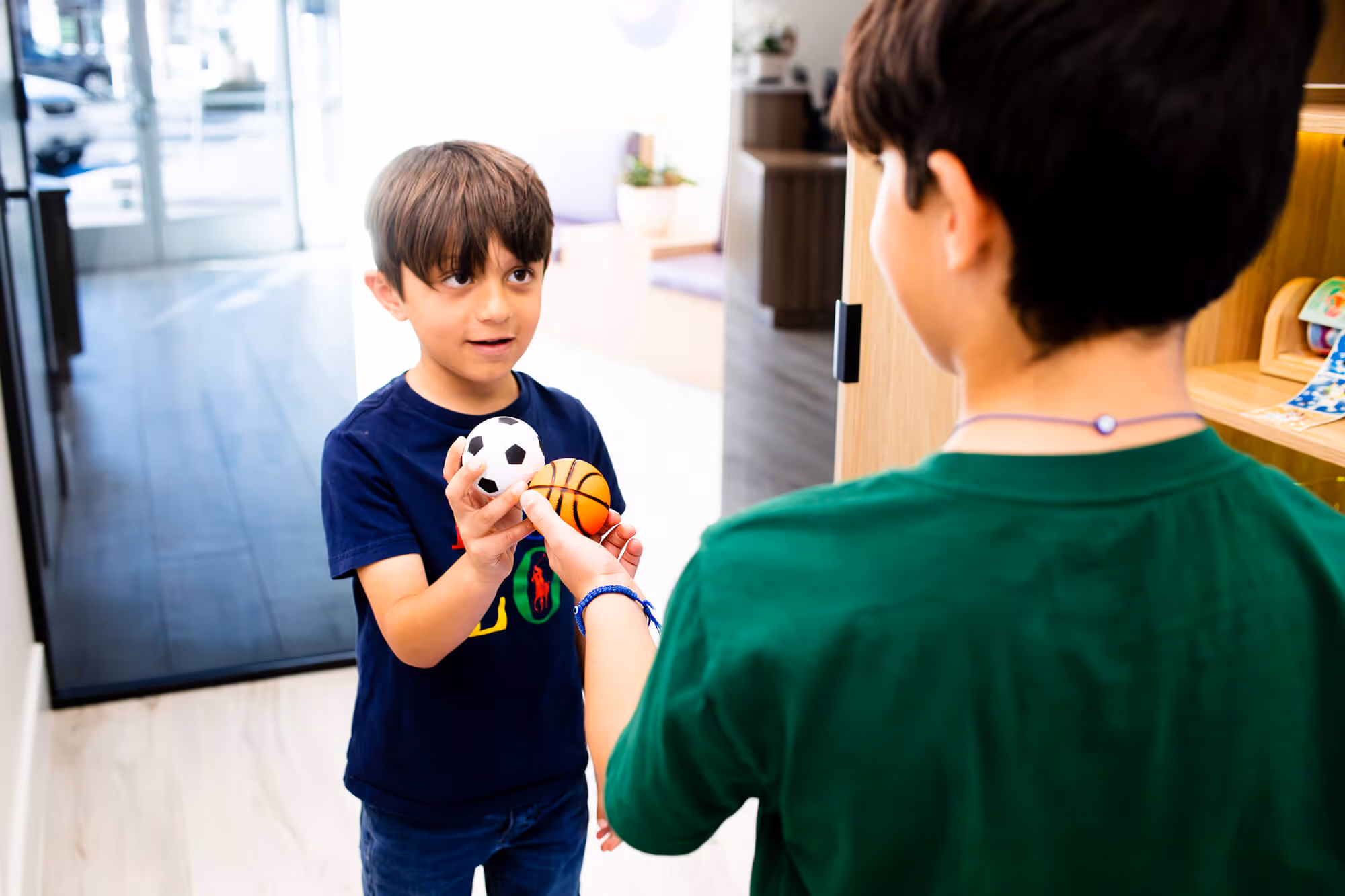 A young boy holding a basketball and a stuffed animal.